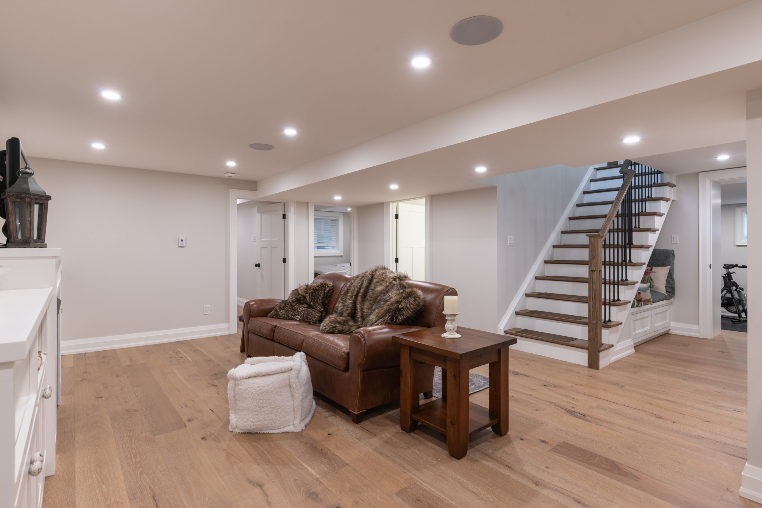 Cozy basement living area with leather couch and wooden stairs