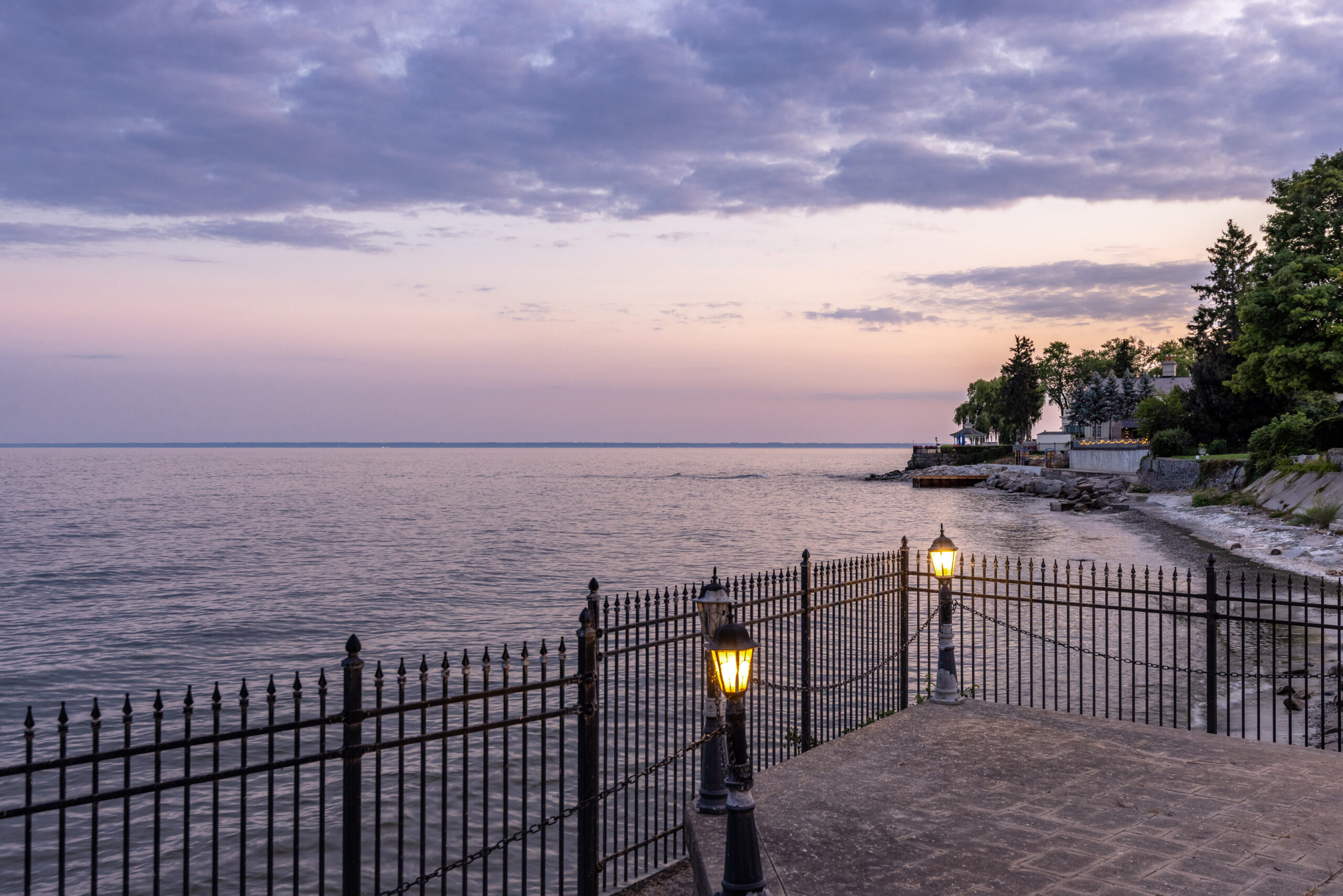 Serene lakeside view at dusk with a fence and lanterns