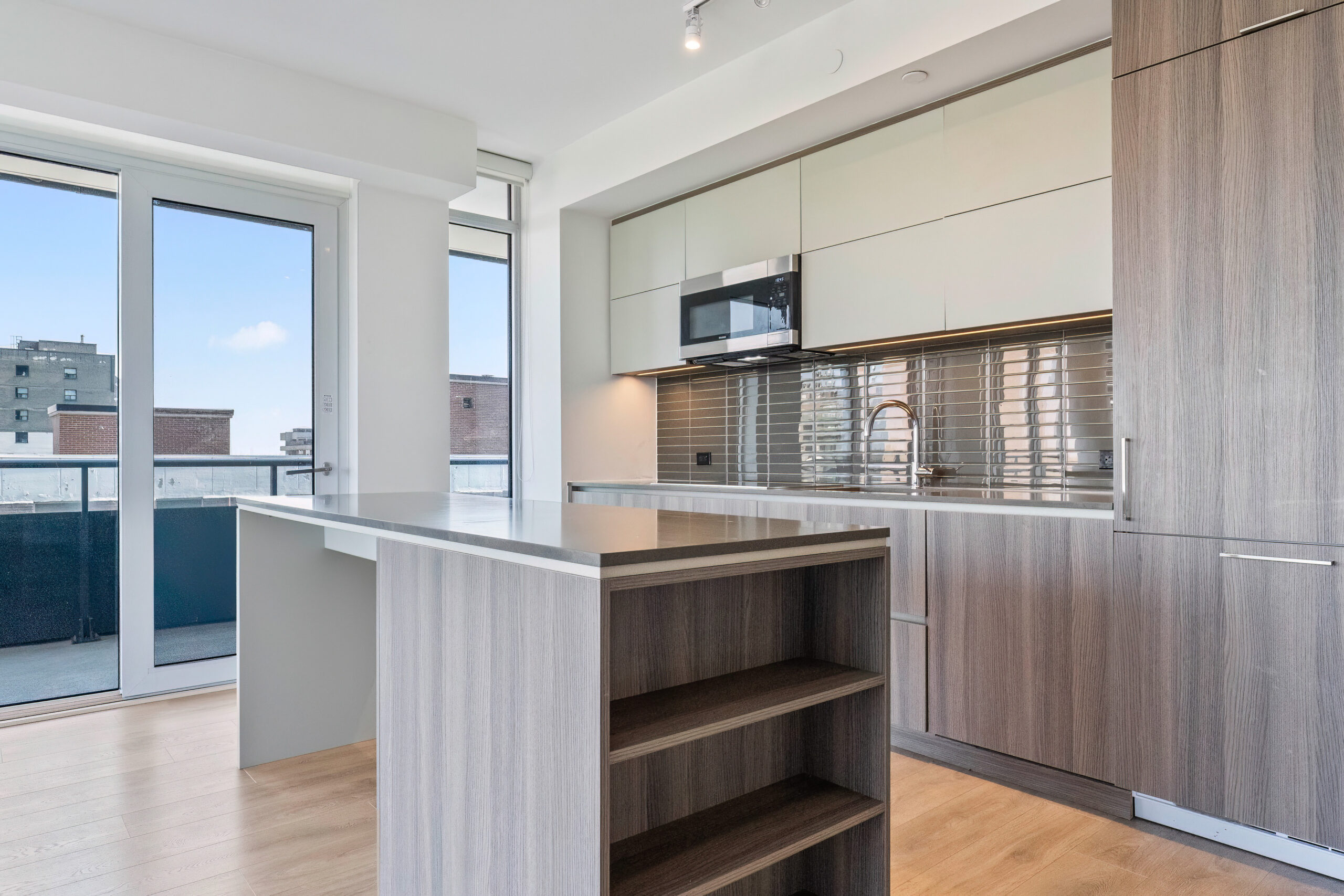 Modern kitchen with wooden cabinets and large windows showcasing a city view