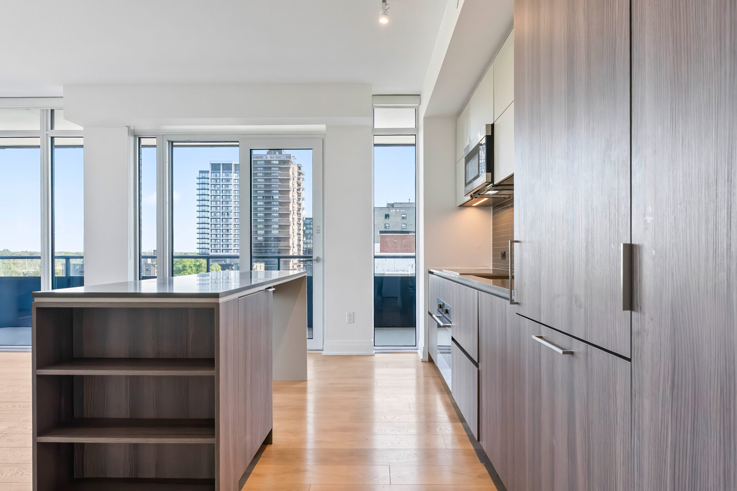Modern kitchen with wooden cabinets and large windows showcasing city views