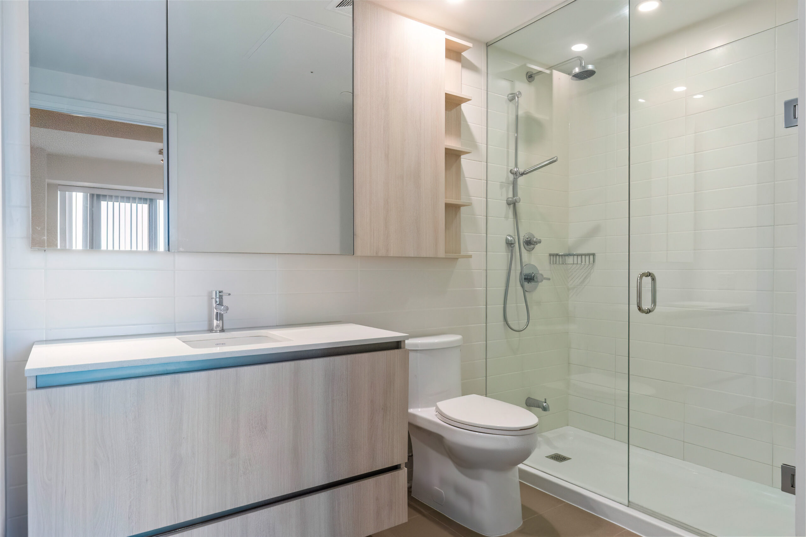 Modern bathroom featuring a glass shower, wooden vanity, and neutral colors