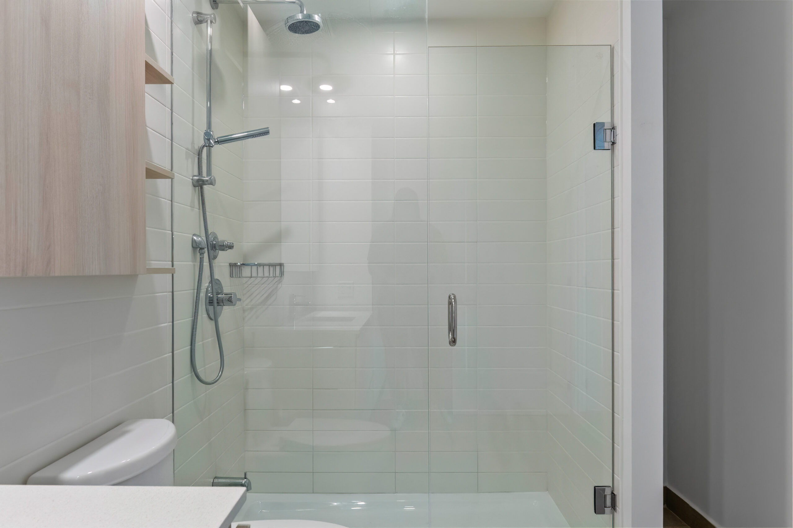 Modern bathroom featuring a glass shower enclosure and wooden shelves