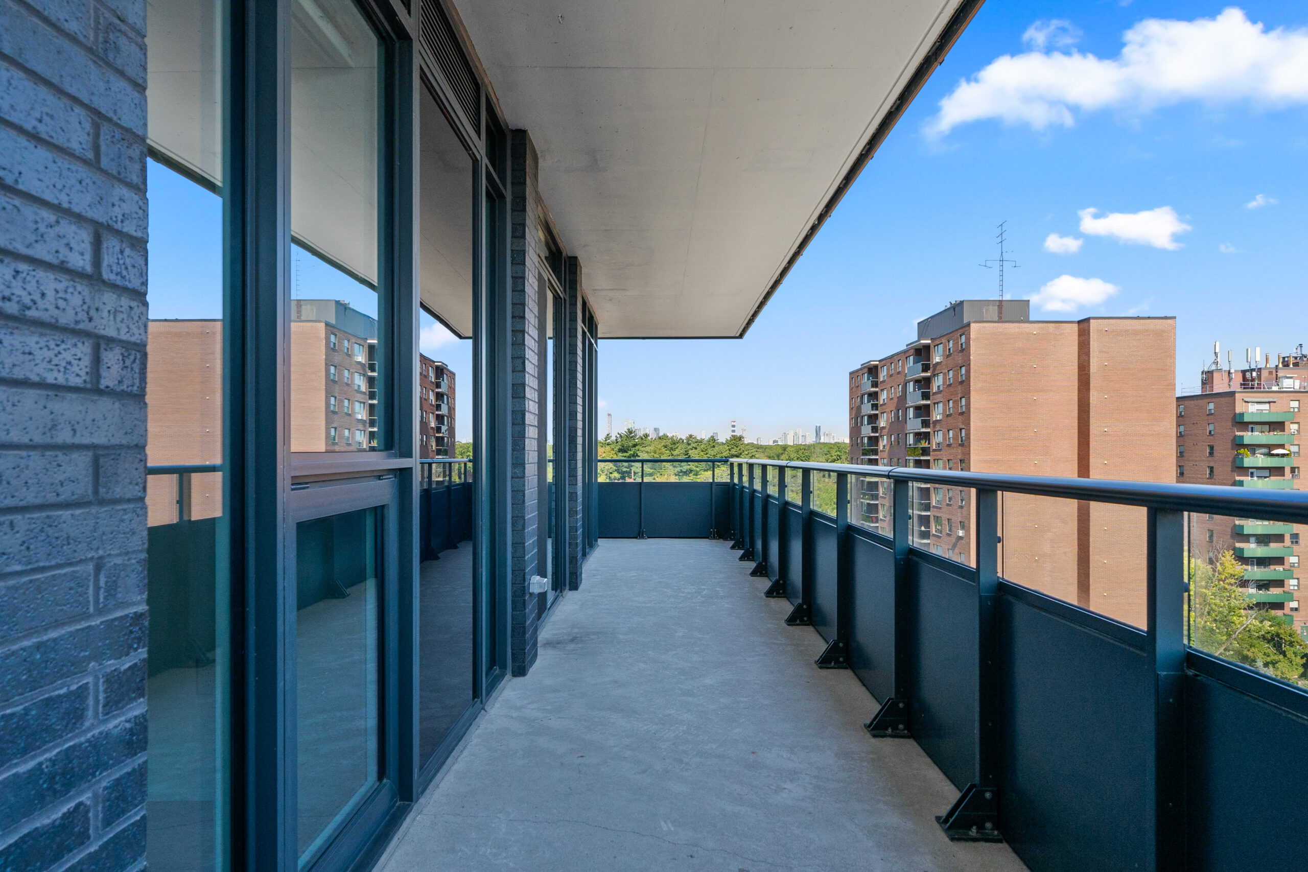 Modern balcony with railing overlooking city buildings and blue sky