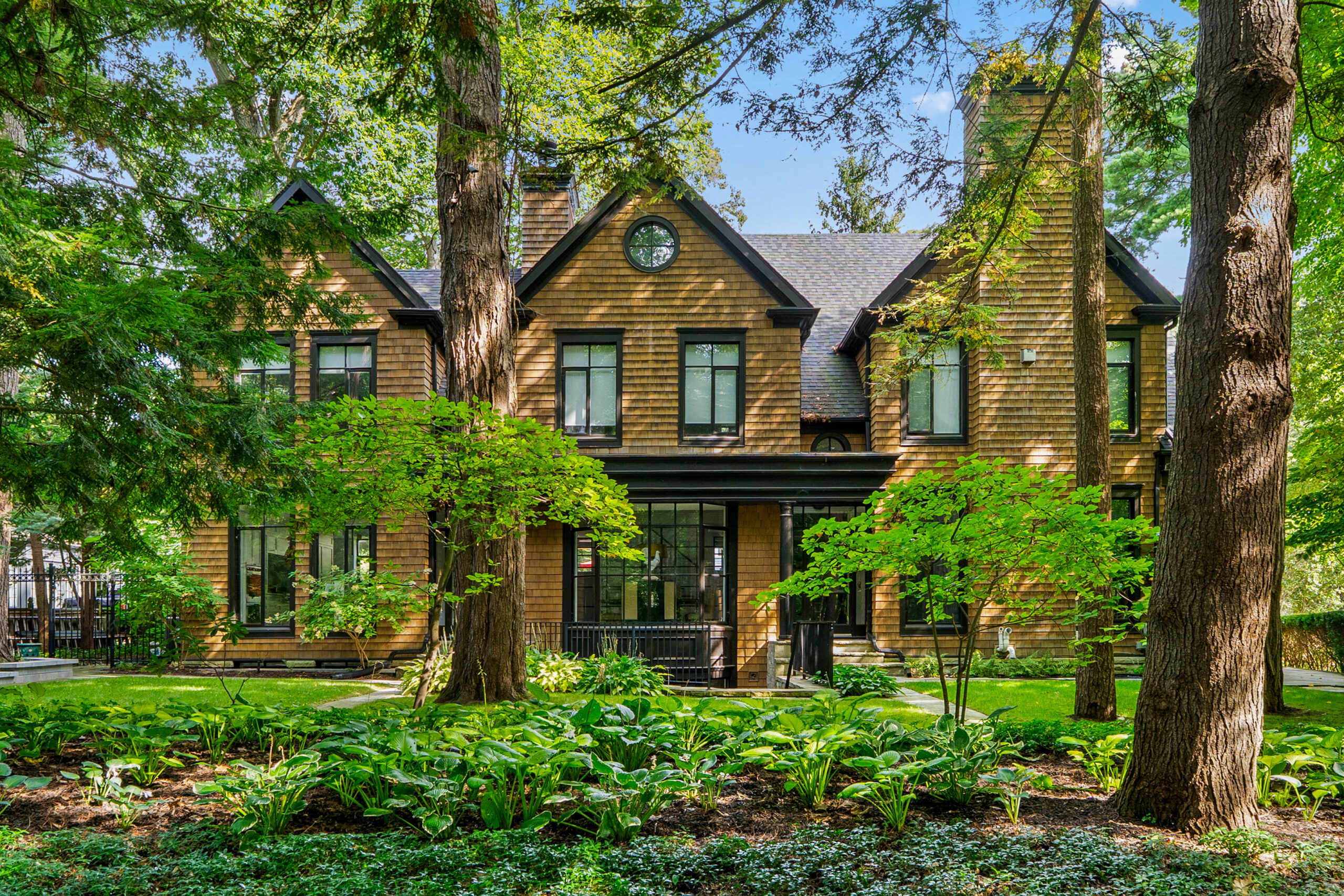 Elegant brick house surrounded by lush greenery and tall trees