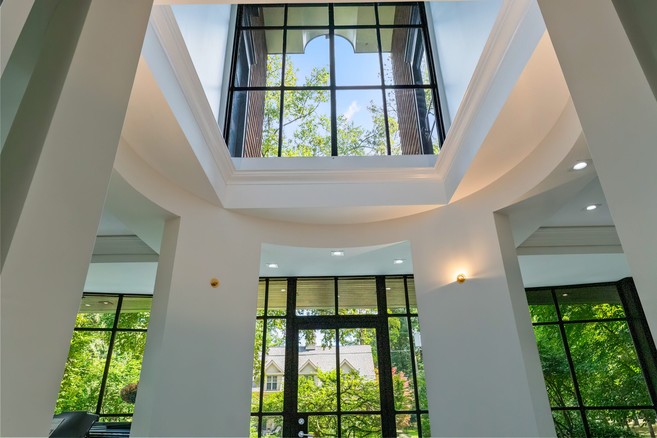 Modern interior with large windows and skylight, surrounded by greenery