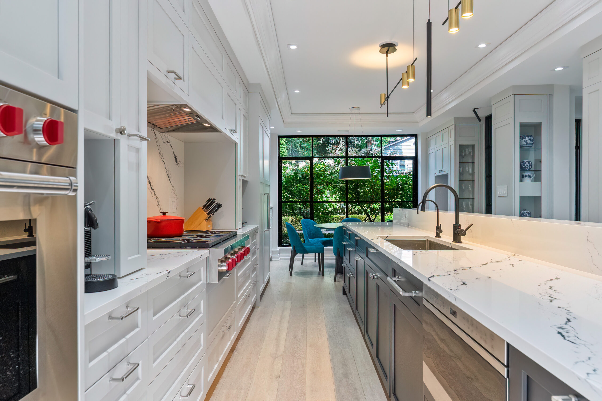 Modern kitchen with white cabinets, marble countertops, and large windows.
