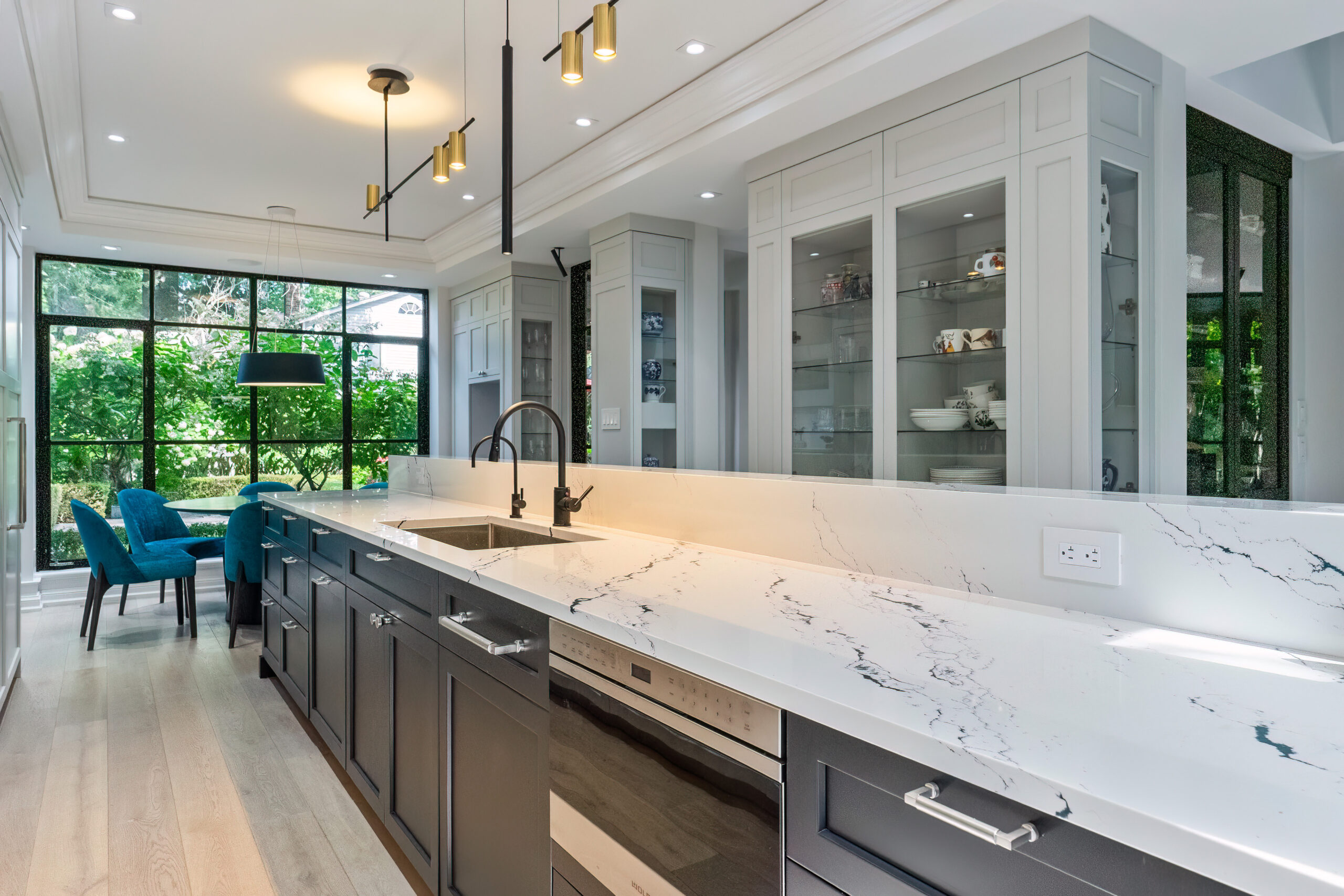 Modern kitchen with marble countertops, dark cabinetry, and large windows.