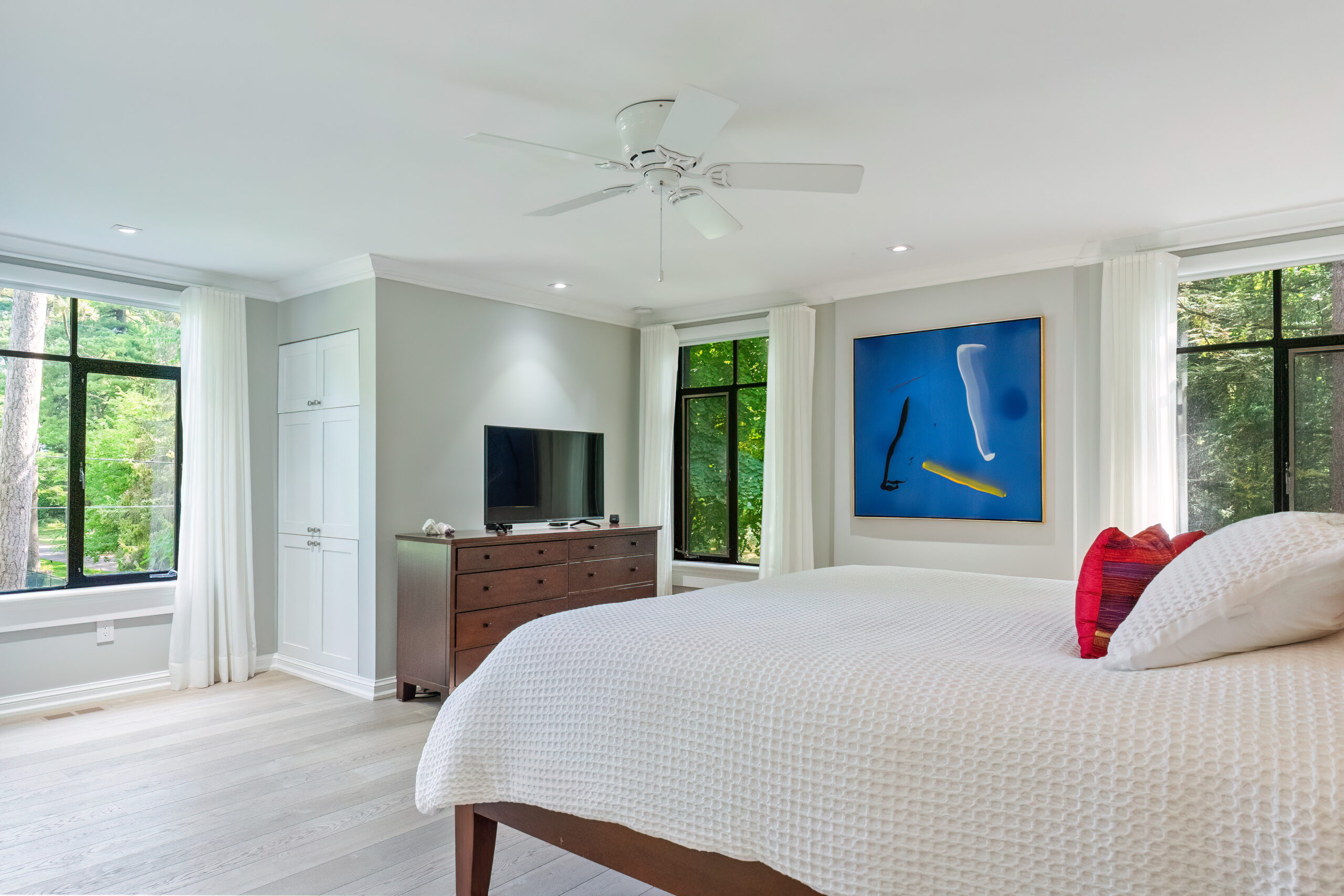 Bright bedroom with large windows, modern decor, and abstract wall art