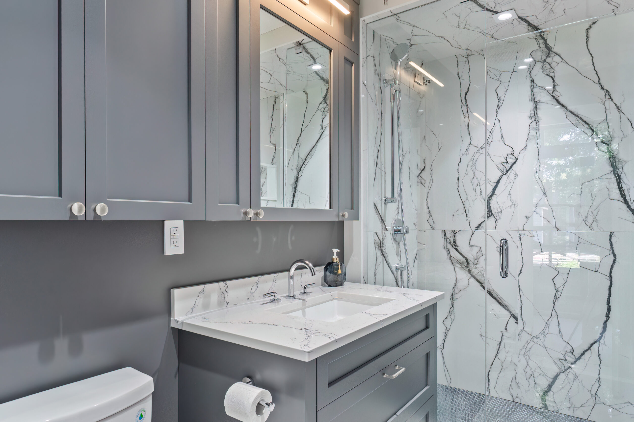 Modern bathroom with gray cabinetry and marble shower walls