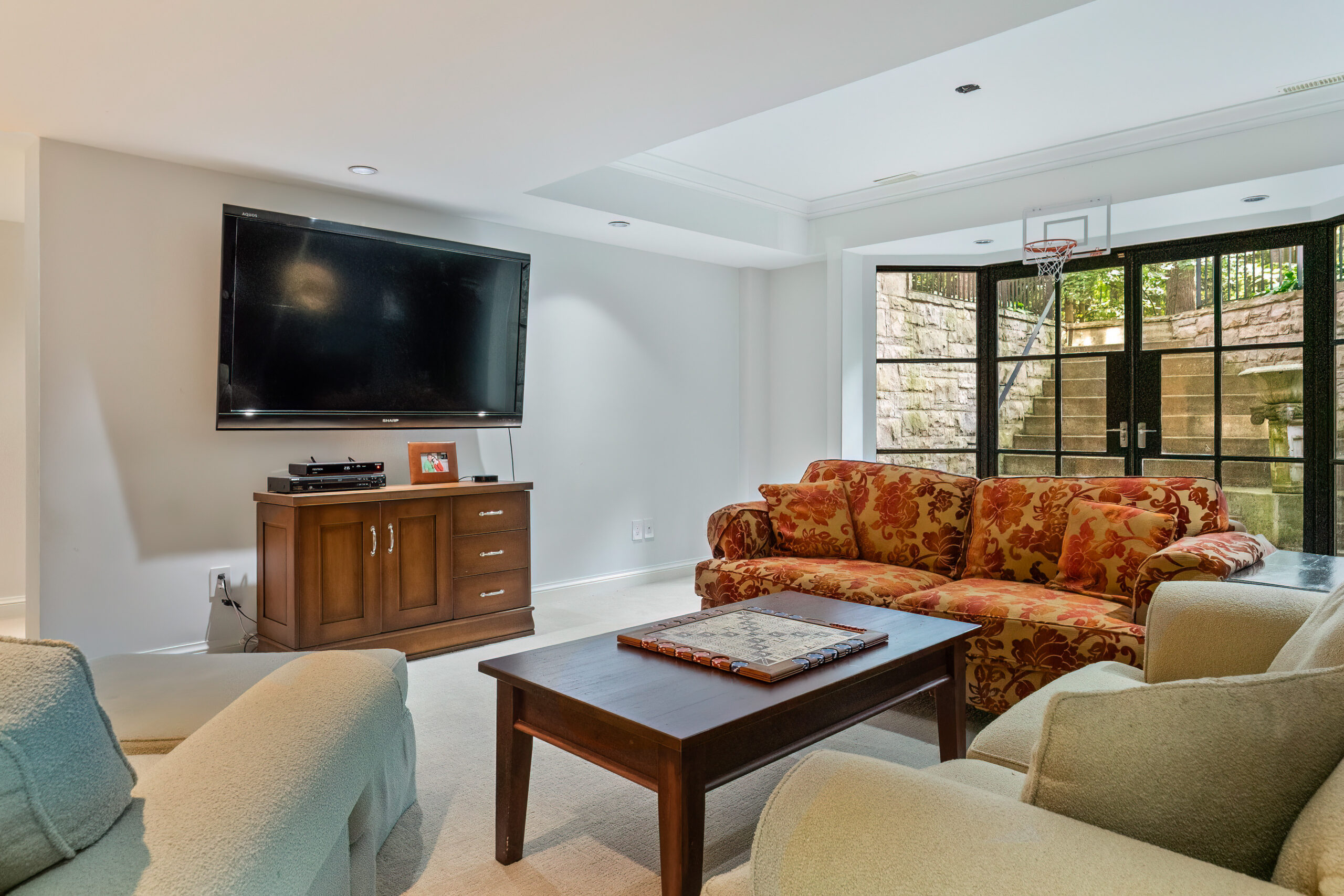 Cozy living room with a large TV, colorful sofa, and wooden coffee table
