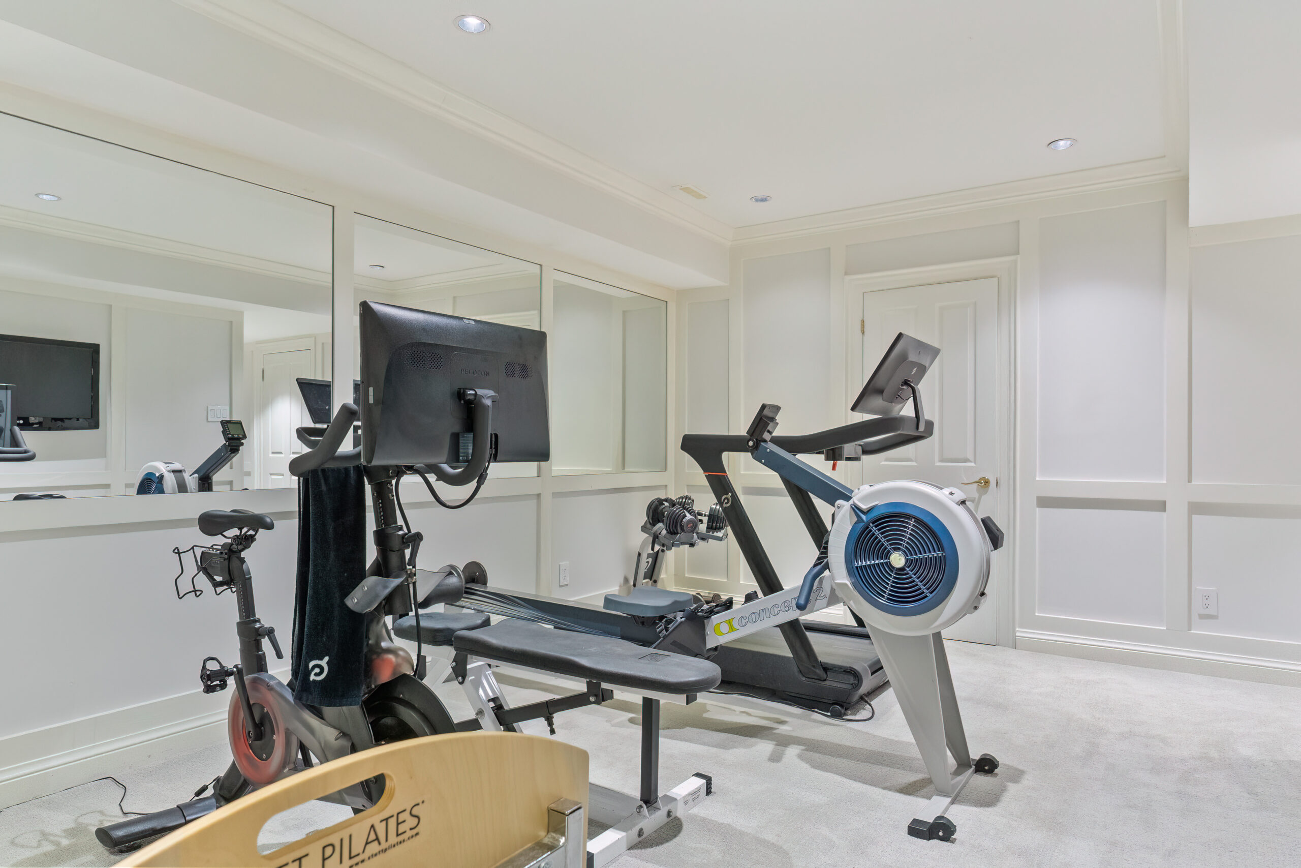 Home gym featuring a rowing machine and stationary bike with mirrors
