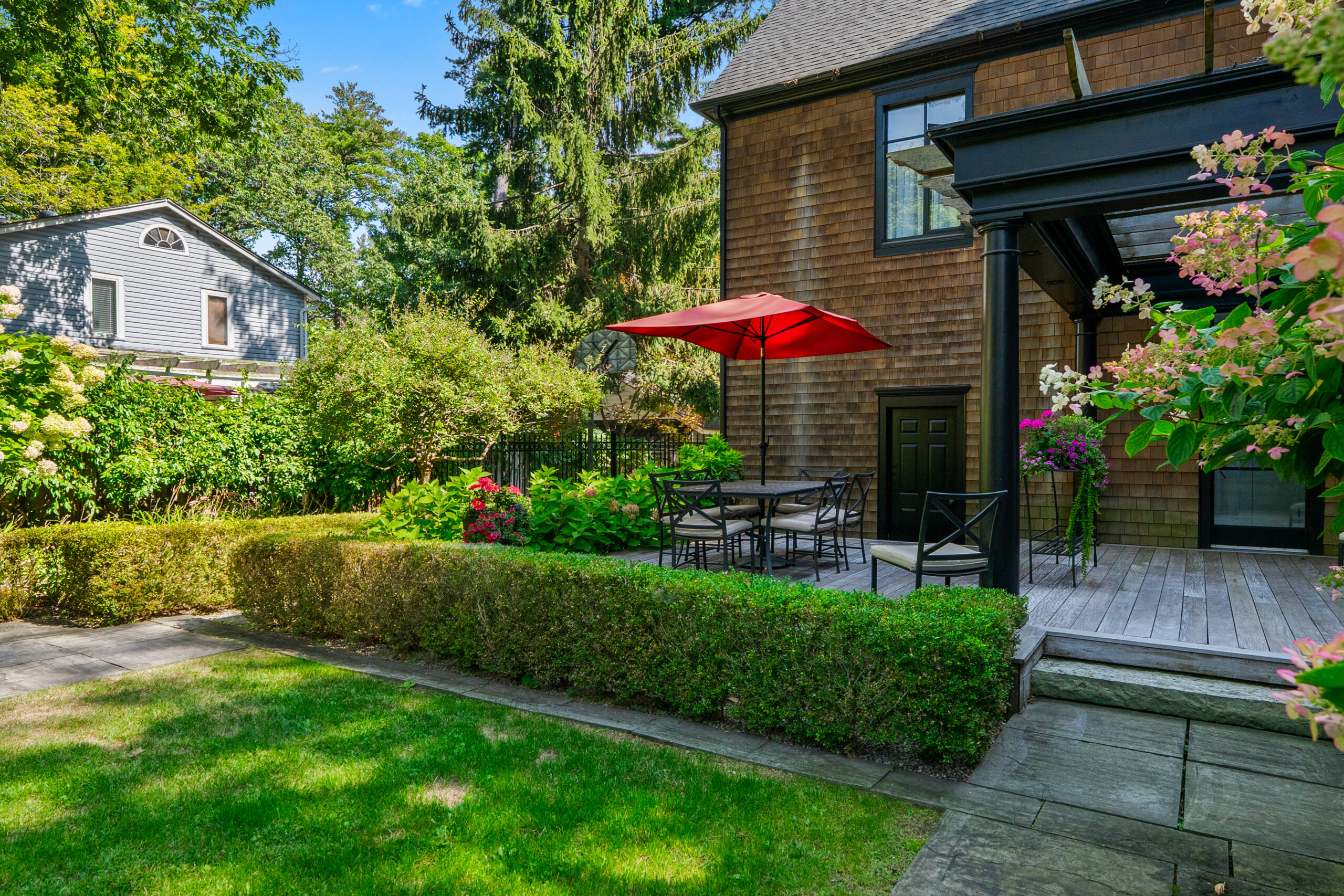 Cozy backyard patio with red umbrella and lush greenery
