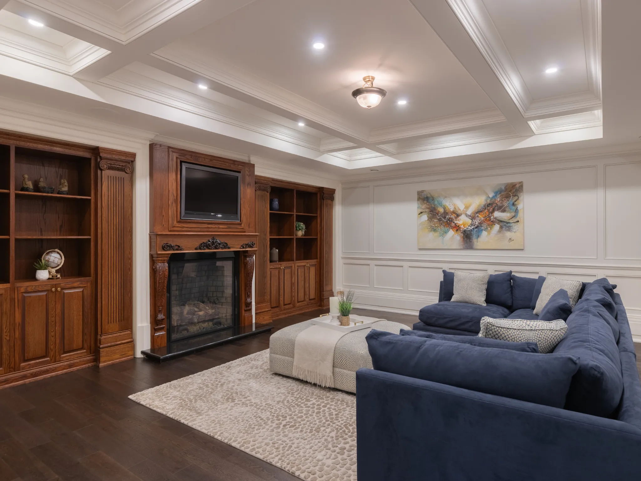 lower level living room featuring coffered ceiling, fireplace and beautiful custom millwork