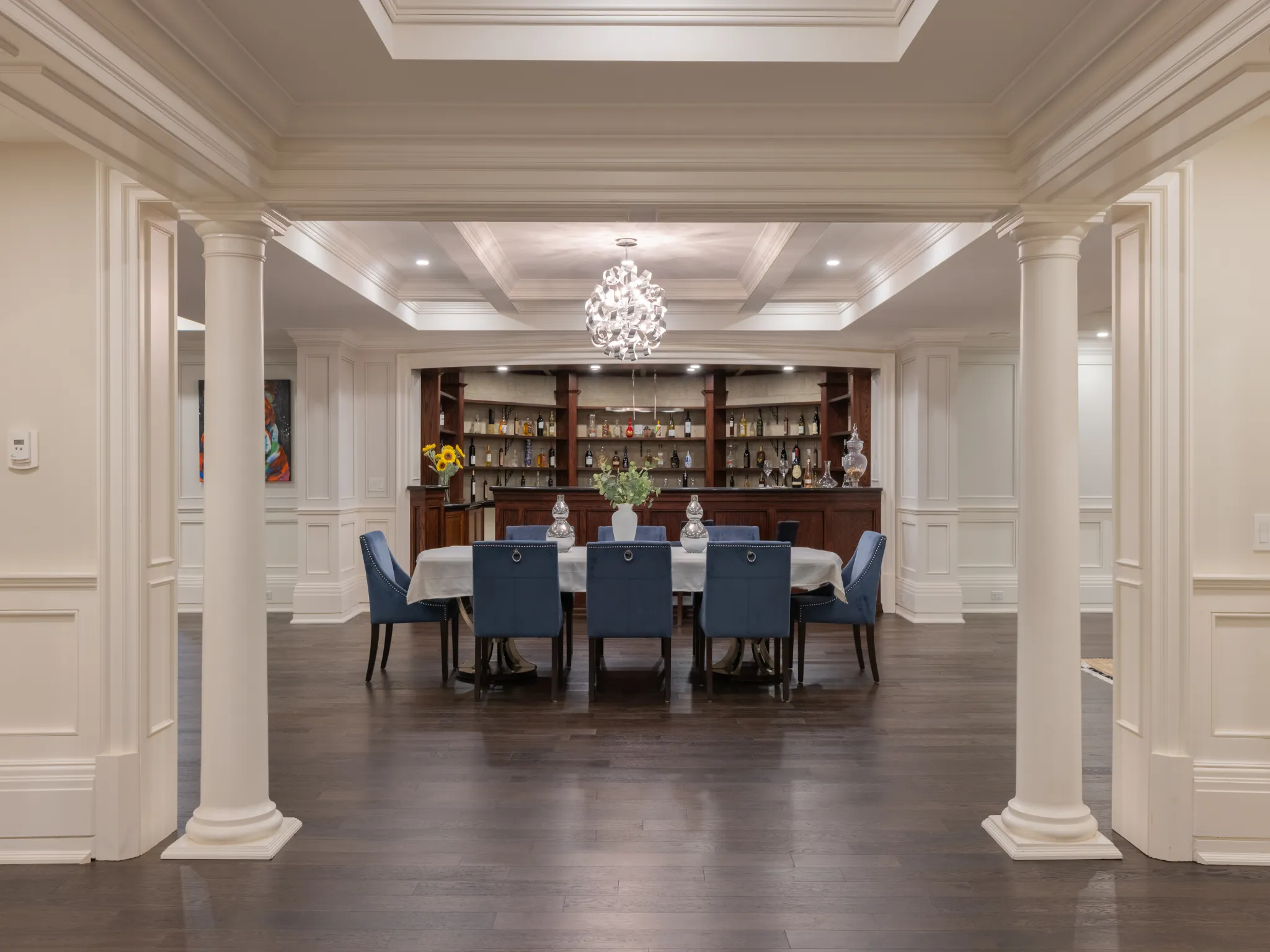 lower level dining space with ornate columns and chandelier