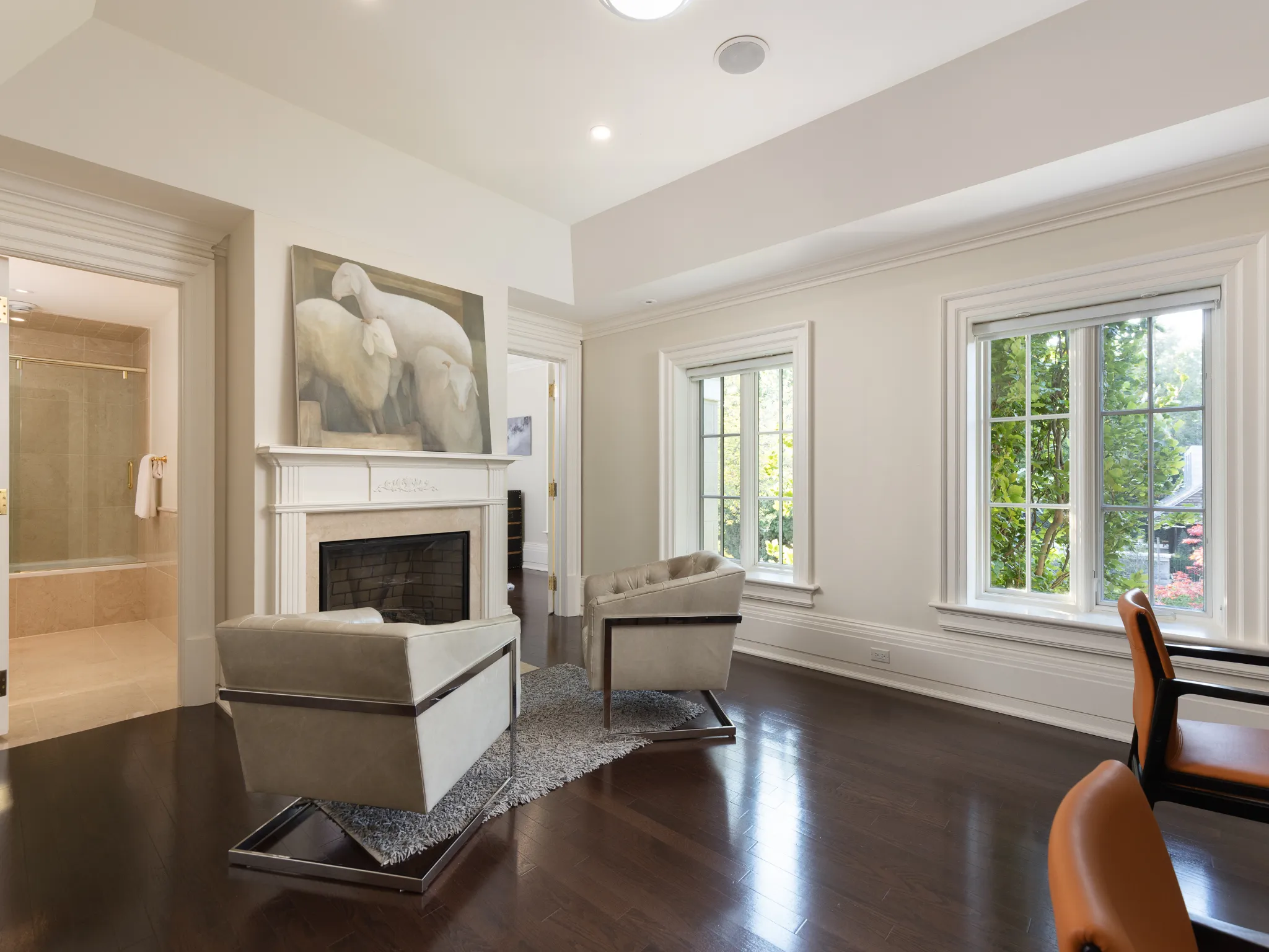 sitting room with fireplace and large windows. Club chairs flank the fireplace