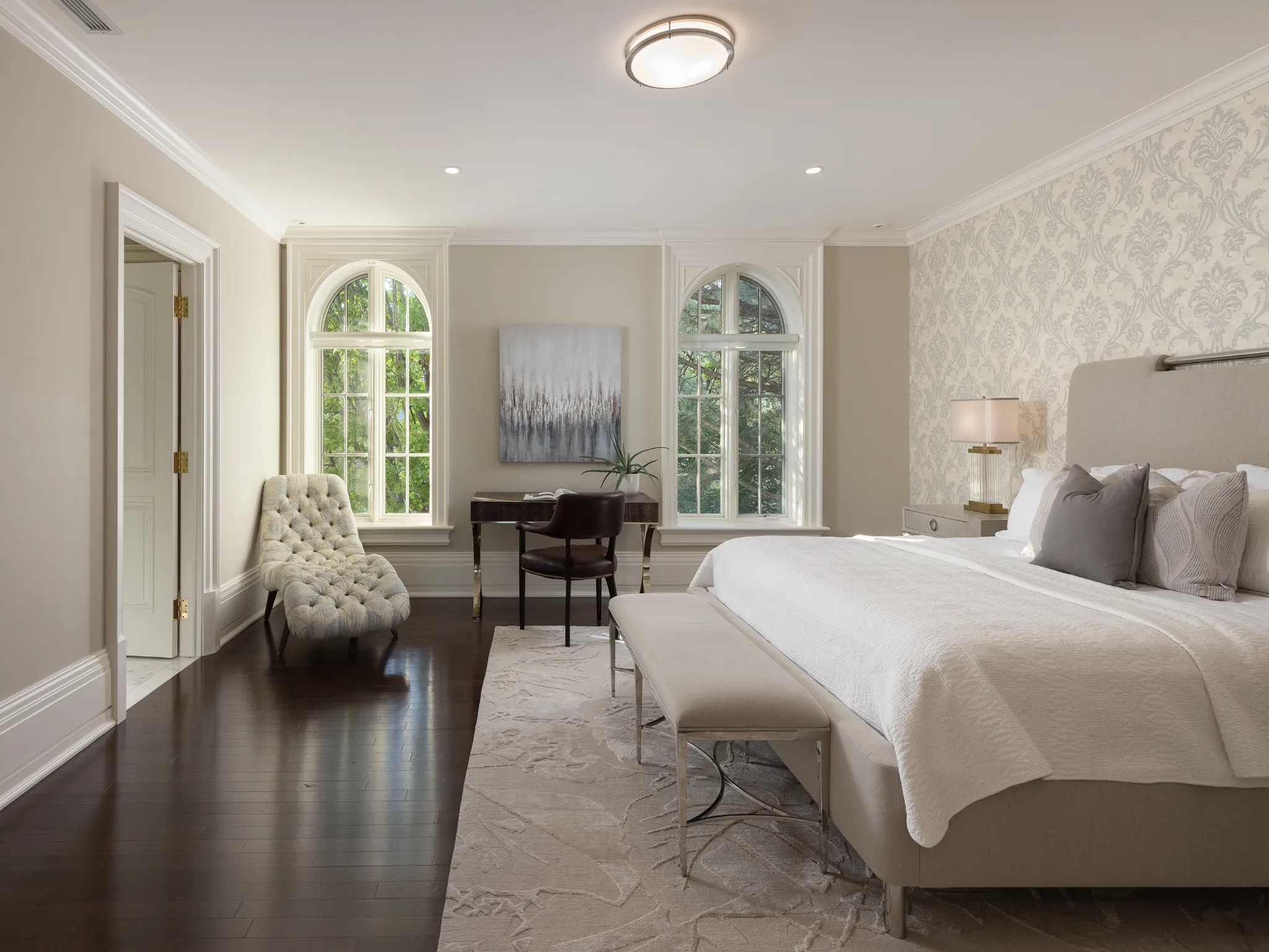 bedroom with wallpaper accent wall, and large arch-shaped windows