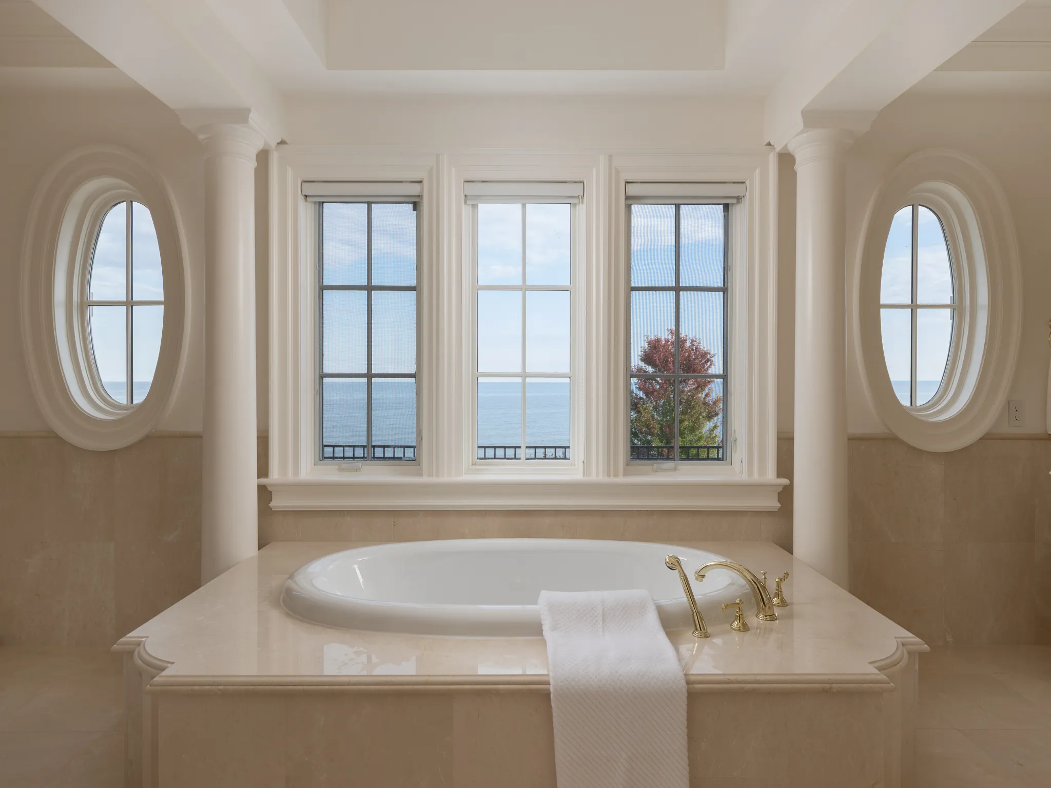 bathroom with decorative columns, soaker tub and water view