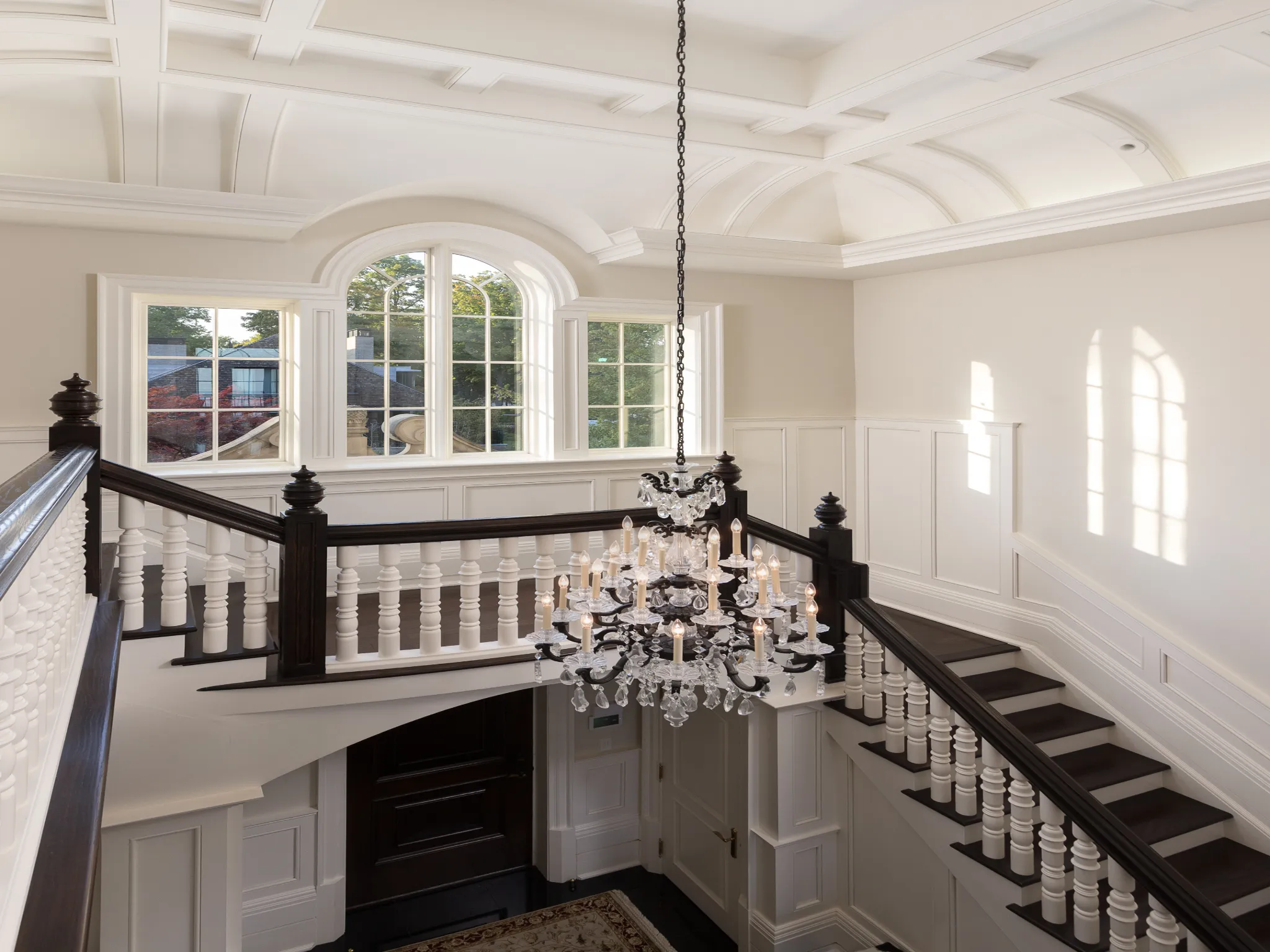 stairway with custom millwork and crystal chandelier