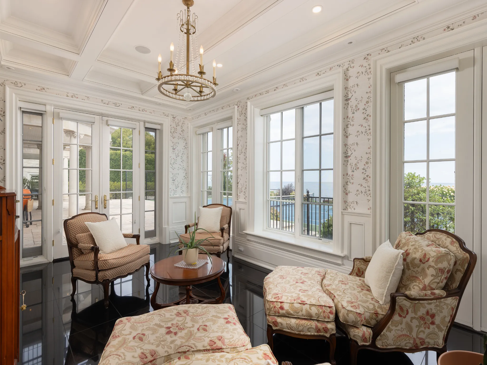 sunroom with french doors, wallpapered walls and a chandelier