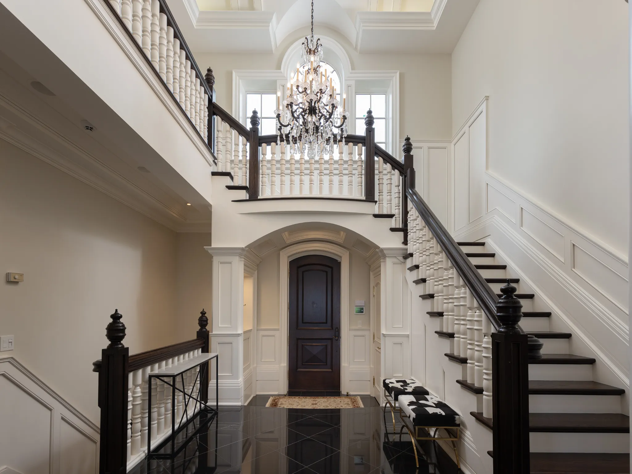 foyer of the home with dark floors and white walls with paneling