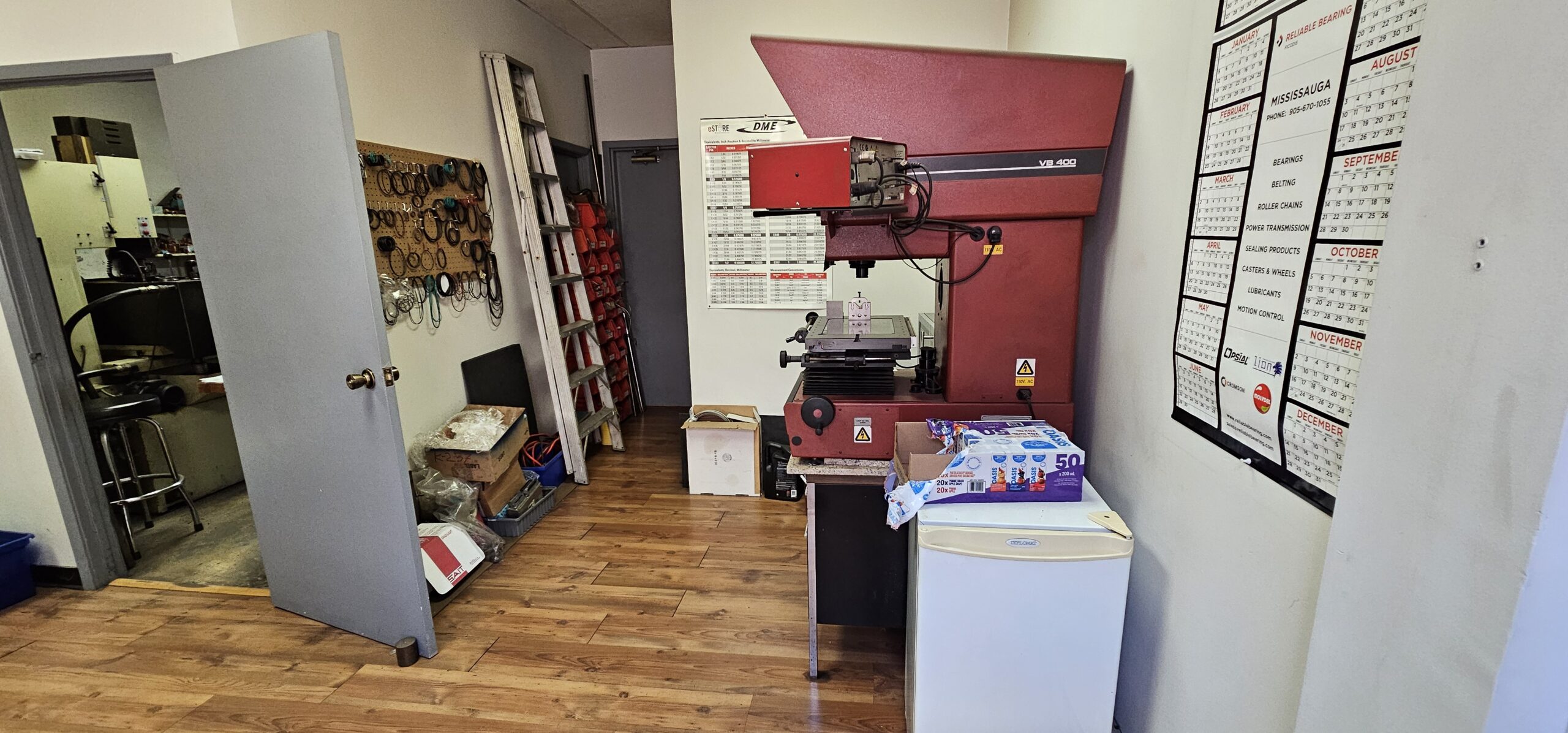 Workshop interior featuring a red machine, white fridge, and calendar on the wall