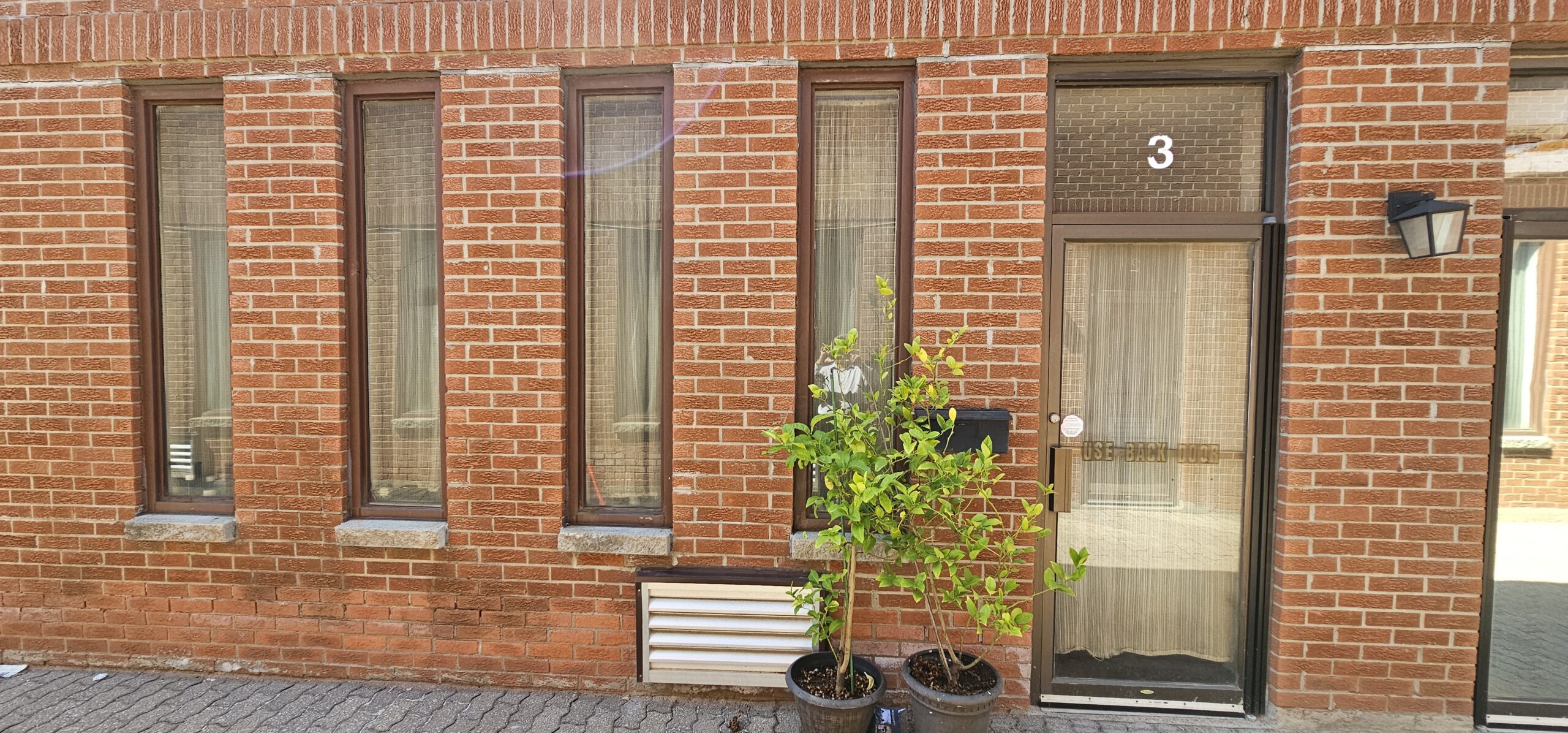 Brick building entrance with large windows and potted plants