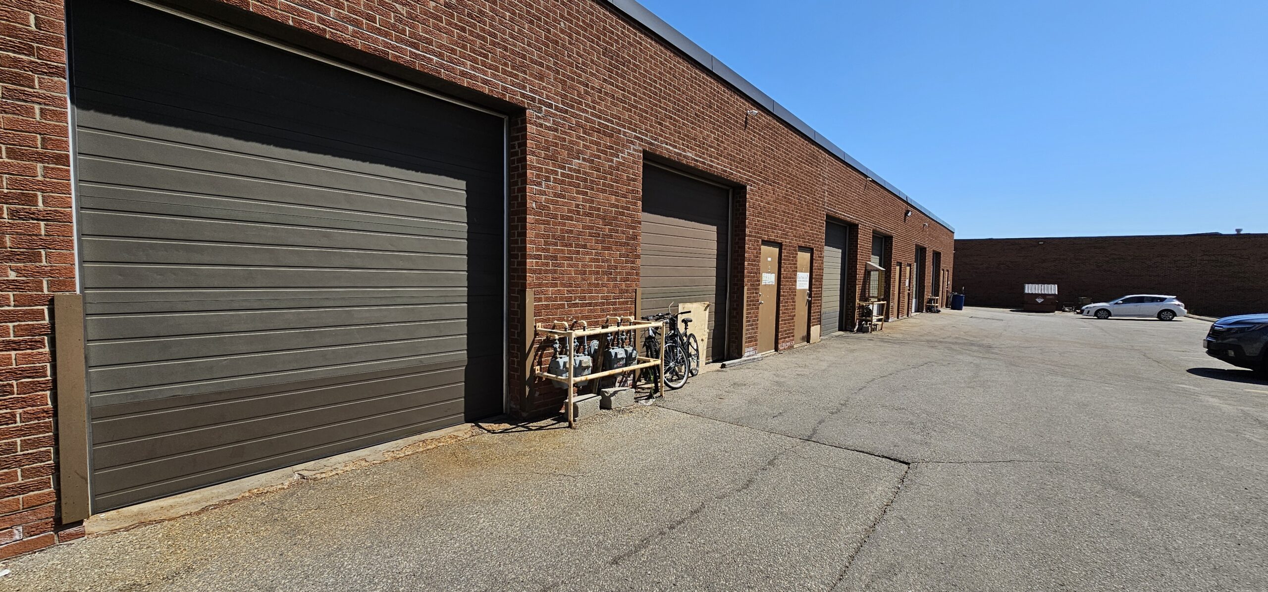 Brick building with multiple garage doors and a clear blue sky