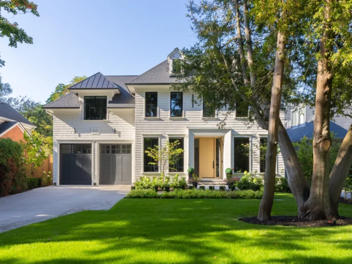 The beautiful exterior of a white custom home with a double car garage and light coloured front door. Green grass and well manicured front lawn