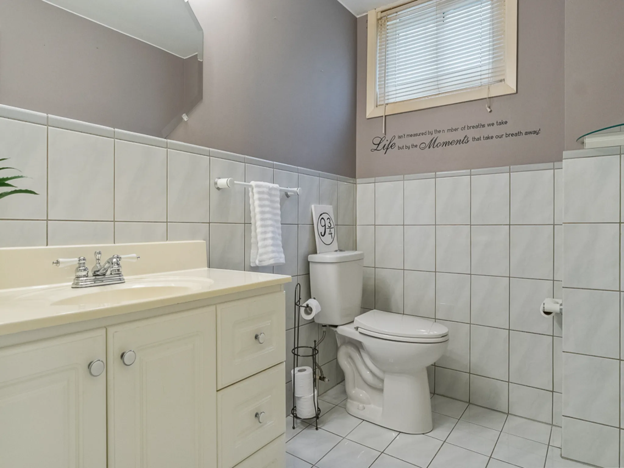 lower level bathroom with white vanity, white tile and window