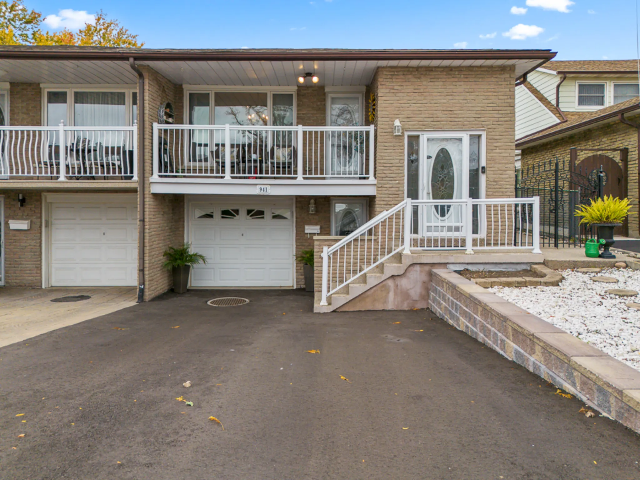 exterior of a semi detached home with large driveway and staircase leading to front door