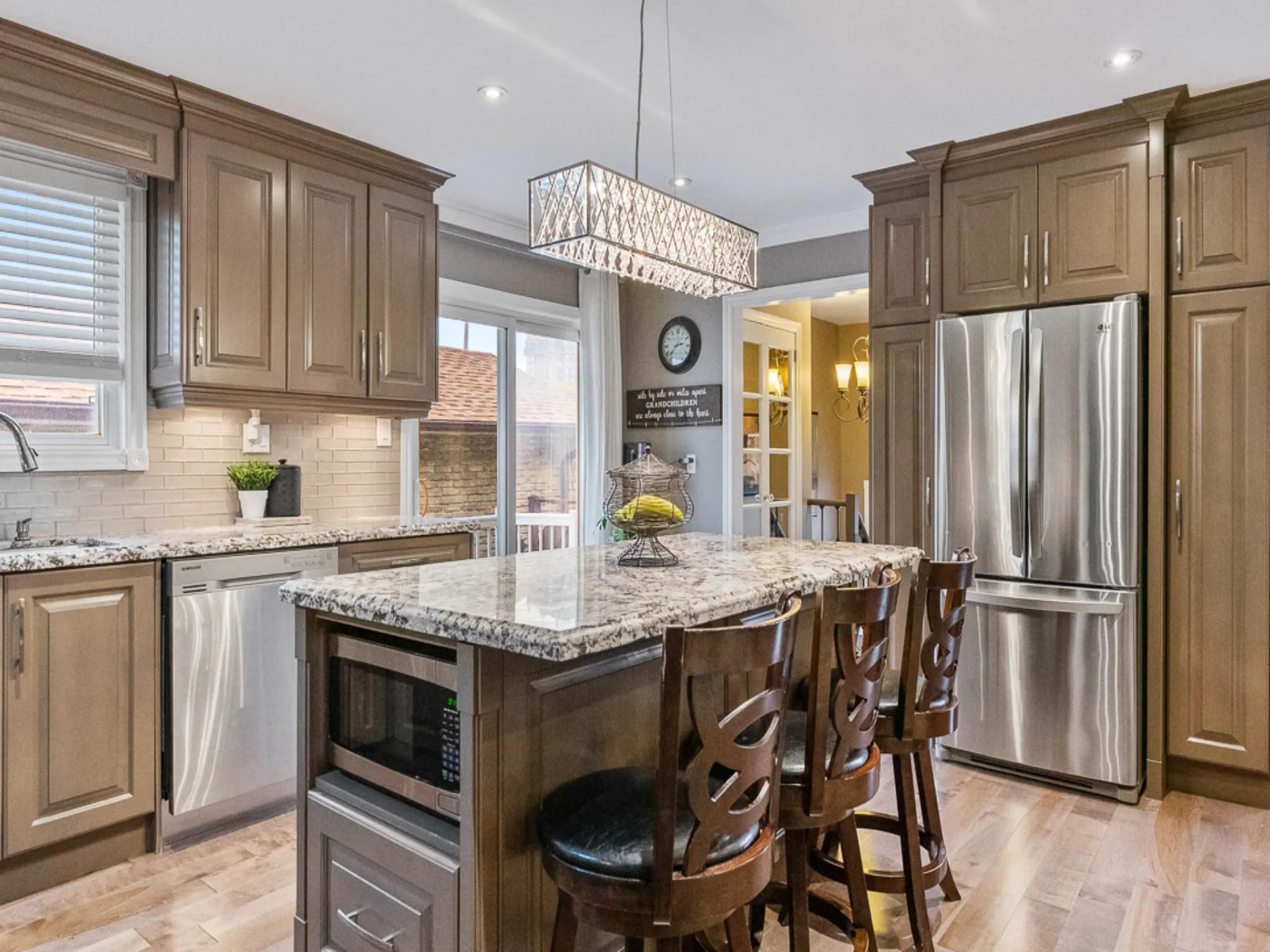 another angle of the kitchen with stainless steel appliances and chandelier