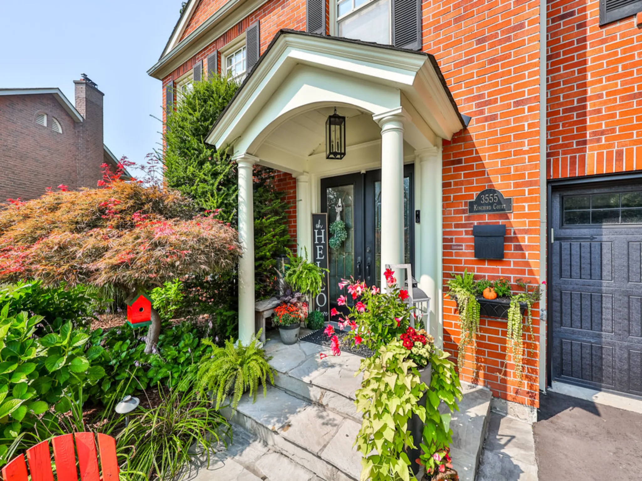 covered front porch with stonework and beautiful flowers and landscaping