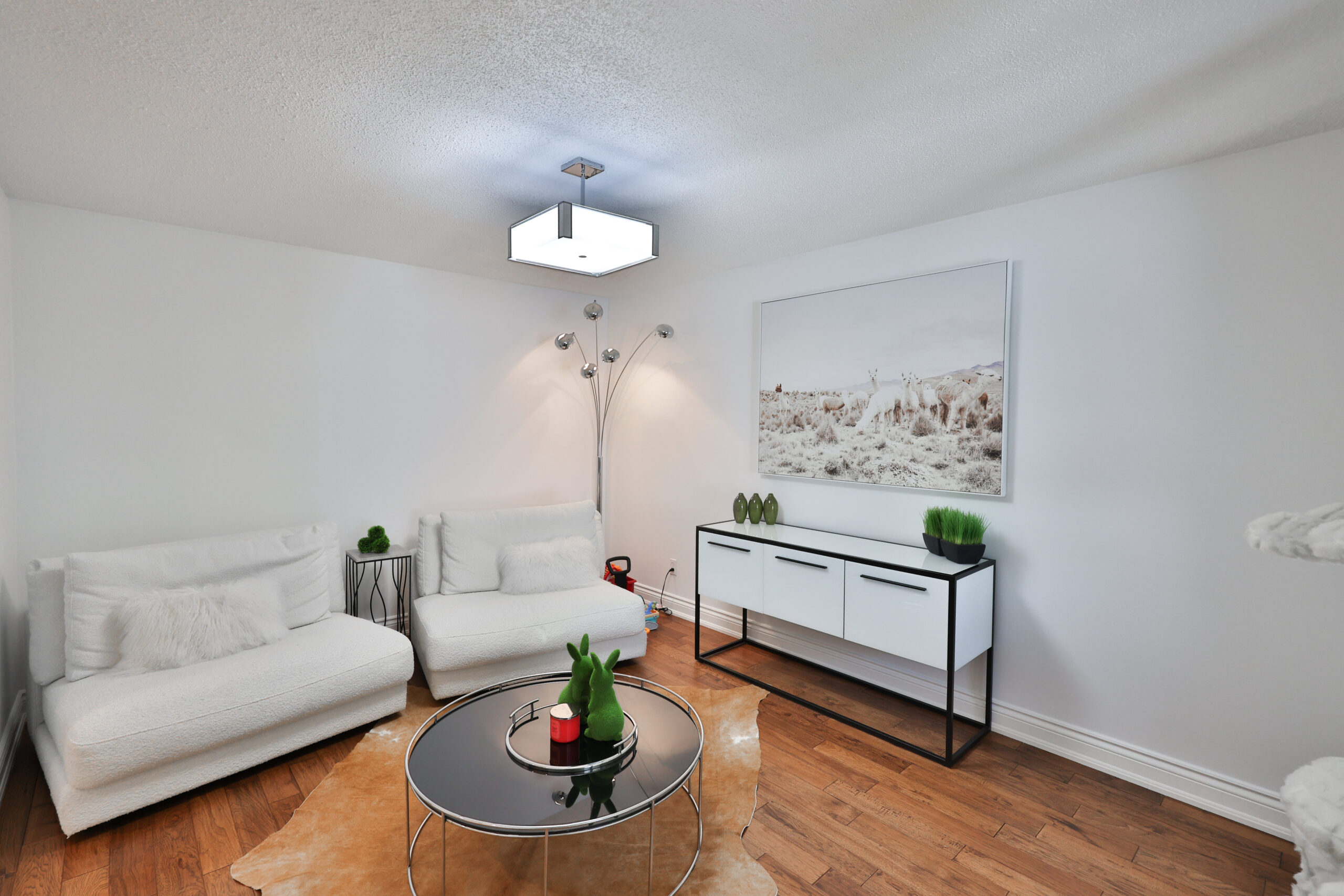Modern living room with white sofas, a round table, and decorative plants
