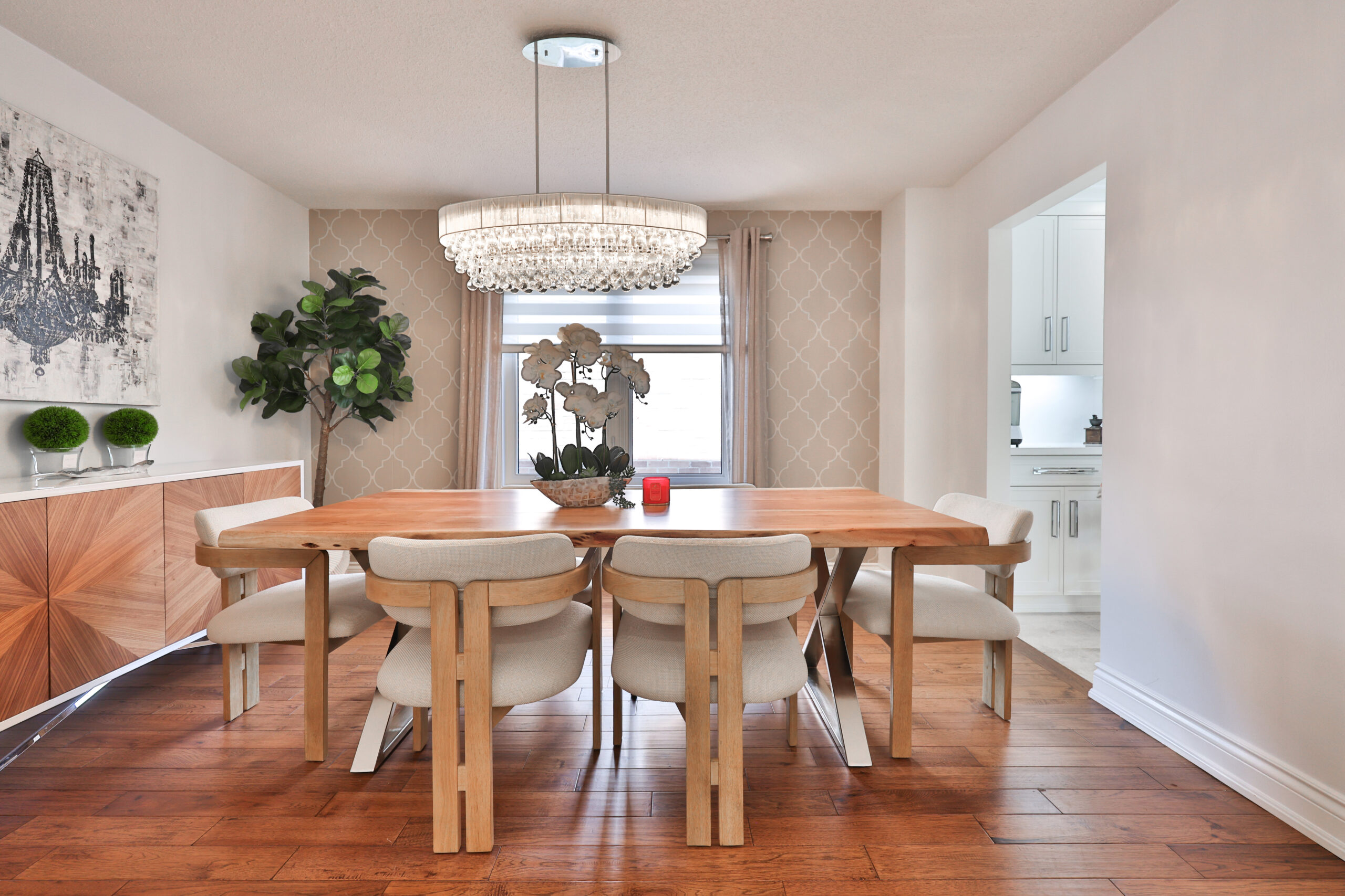 Modern dining room featuring a wooden table, white chairs, and a chandelier