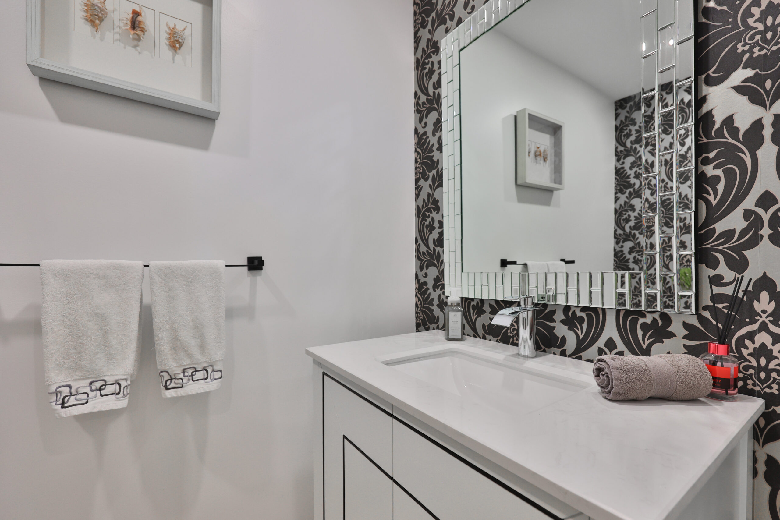 Modern bathroom with patterned wallpaper, sink, and towels hanging.