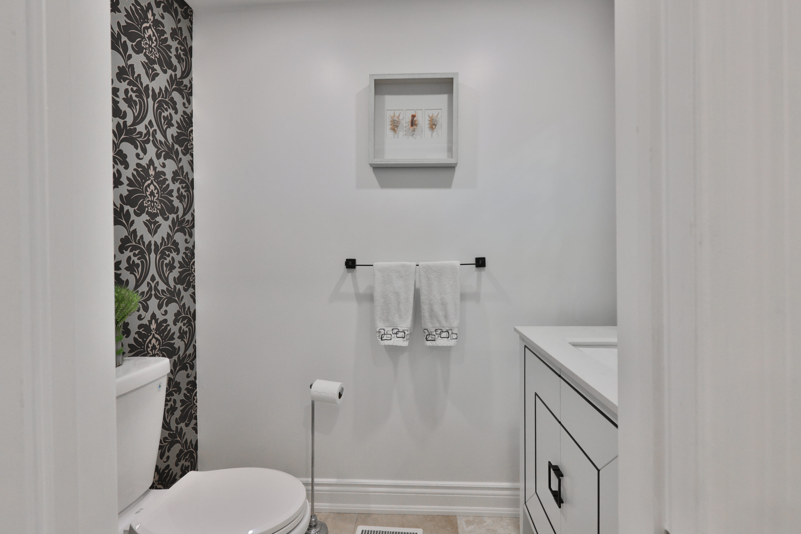 Modern bathroom with black and white wallpaper, towels, and a vanity.
