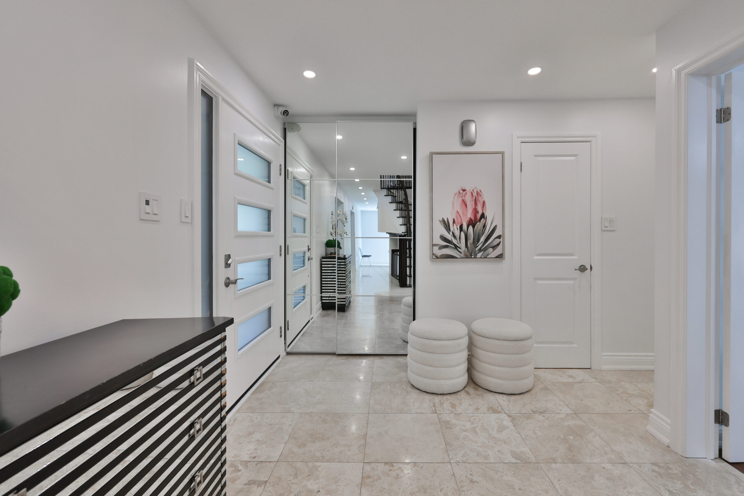 Modern hallway with white walls, sleek doors, and decorative artwork