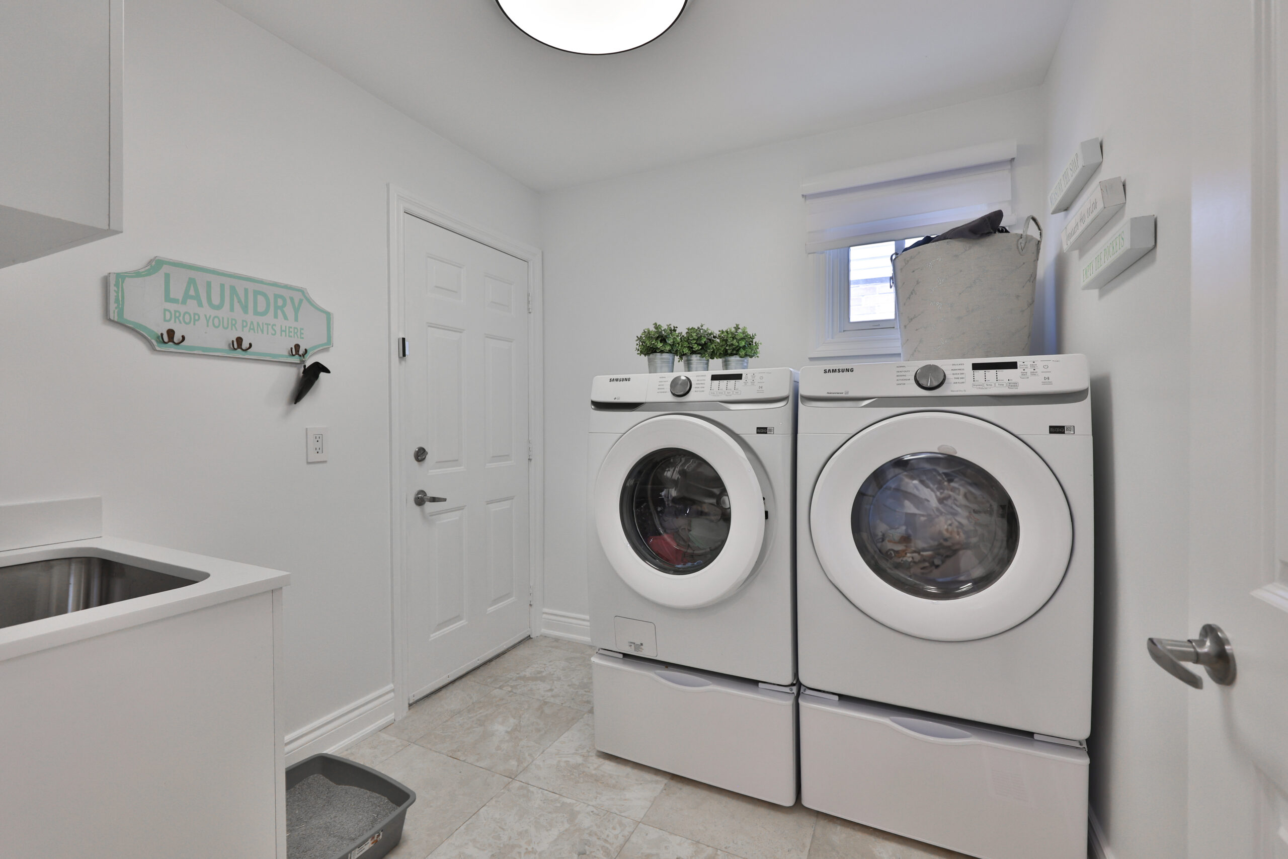 Bright laundry room with stacked washer and dryer, sink, and wall decor
