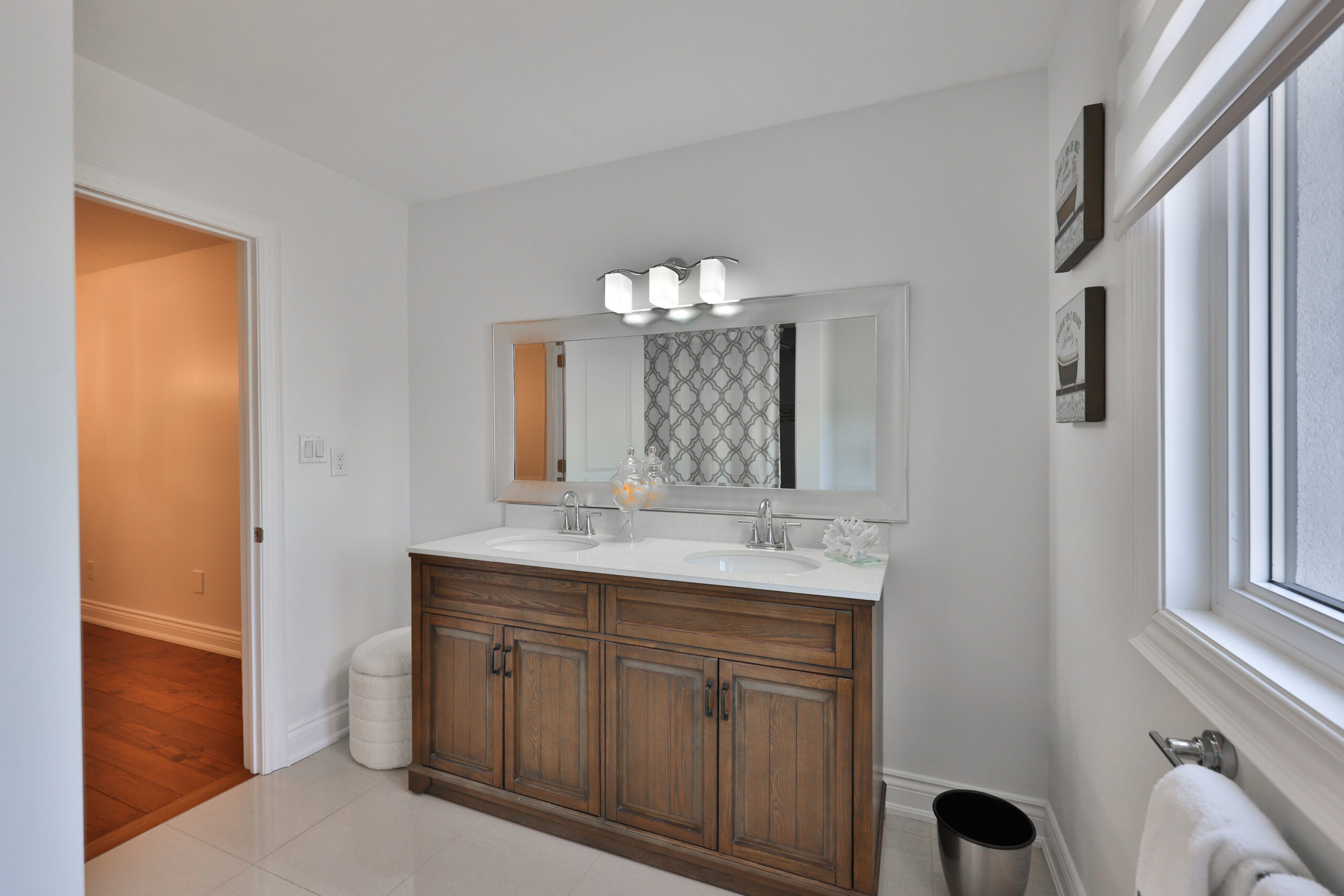 Modern bathroom with wooden vanity, double sinks, and patterned backsplash