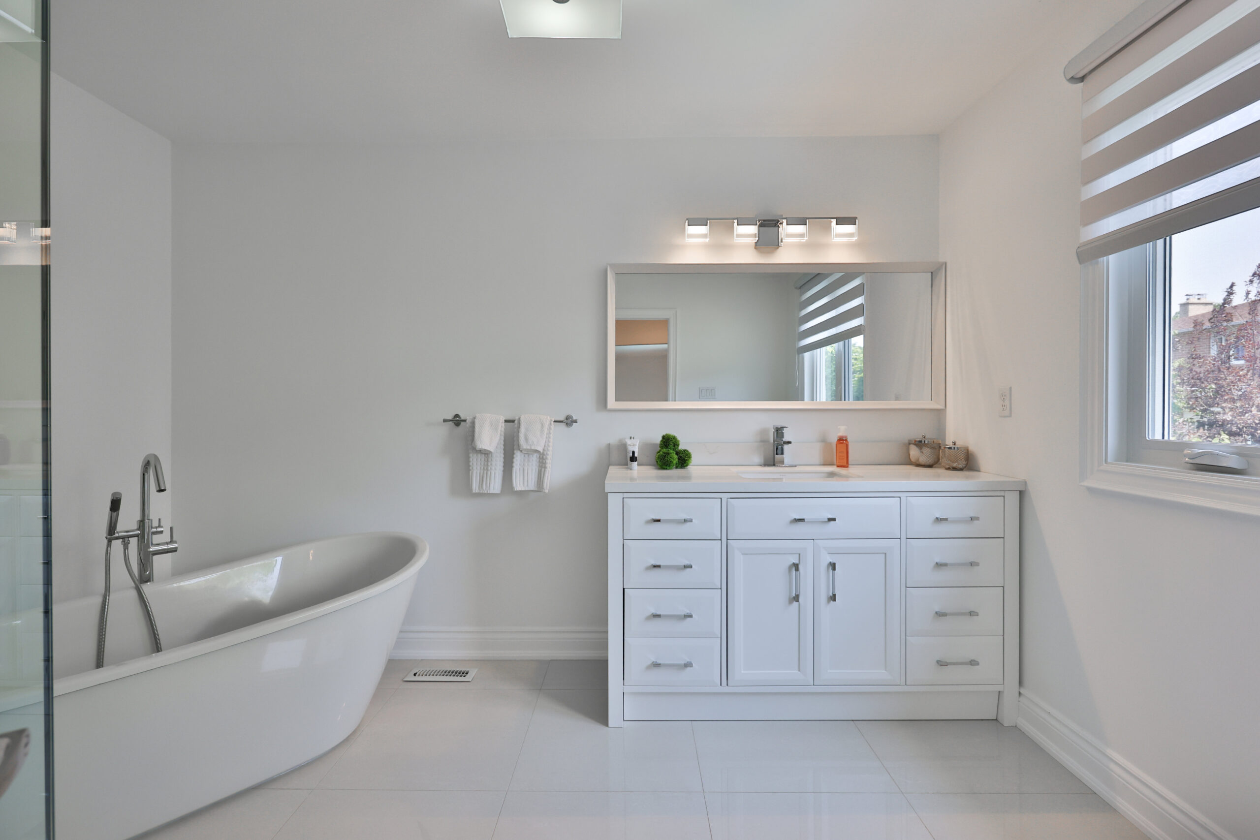 Modern bathroom featuring a freestanding tub and white vanity.