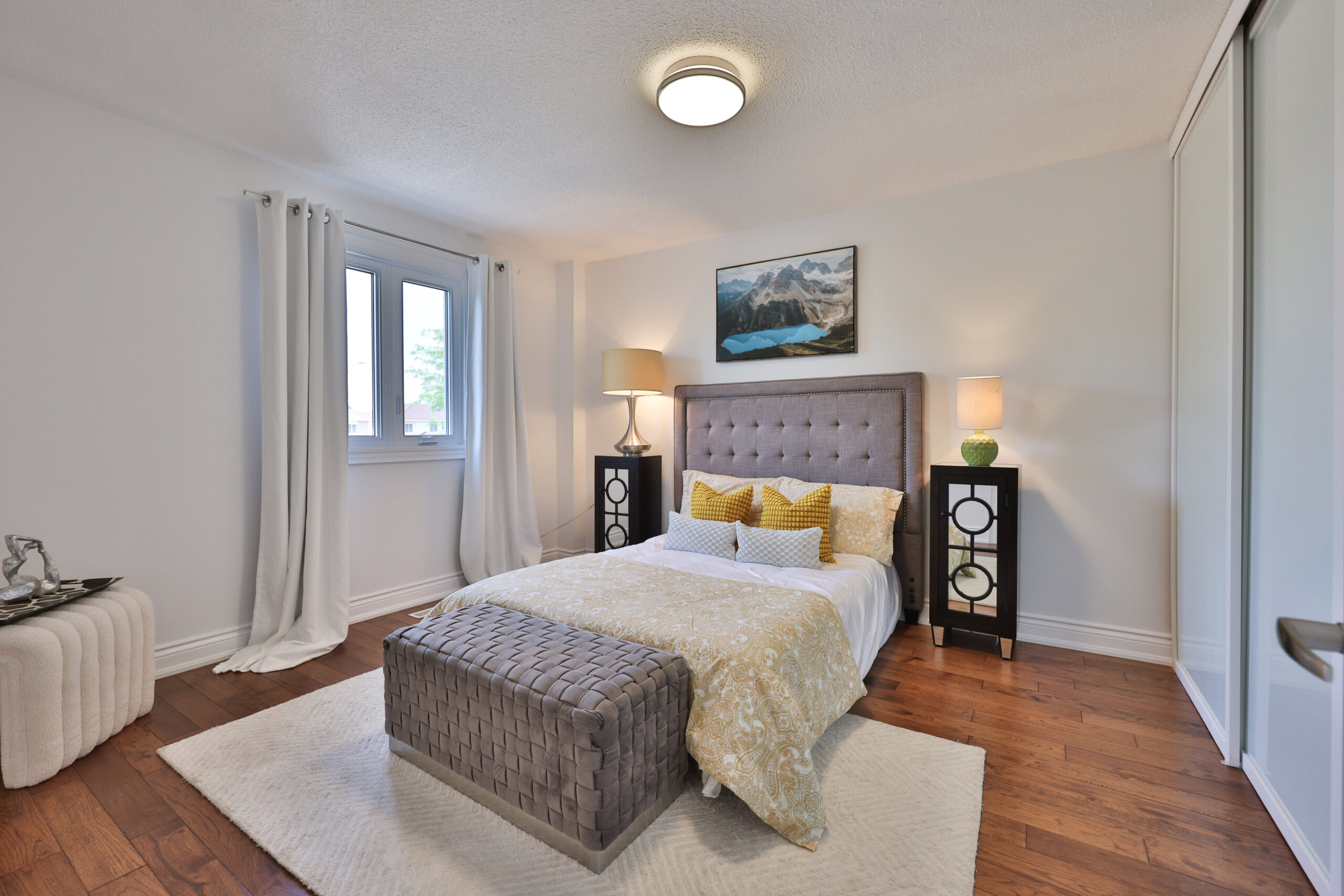 Cozy bedroom with a gray bed, decorative pillows, and wooden flooring