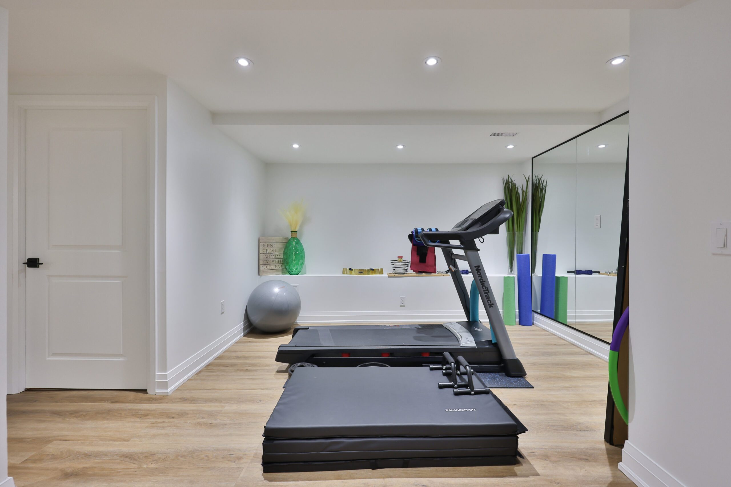 Home gym with treadmill, exercise ball, and colorful workout equipment