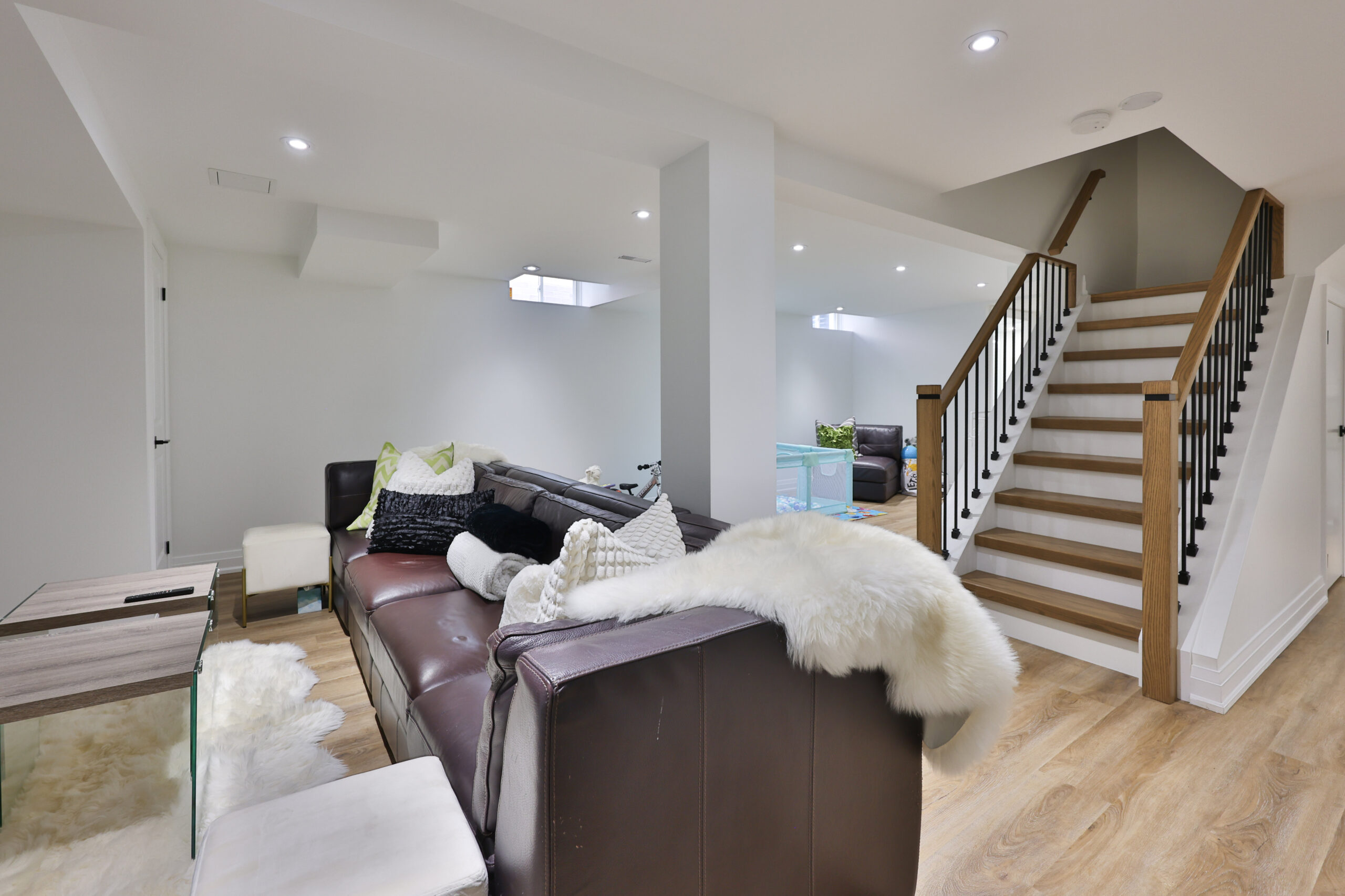 Modern basement living area with a staircase and cozy furniture