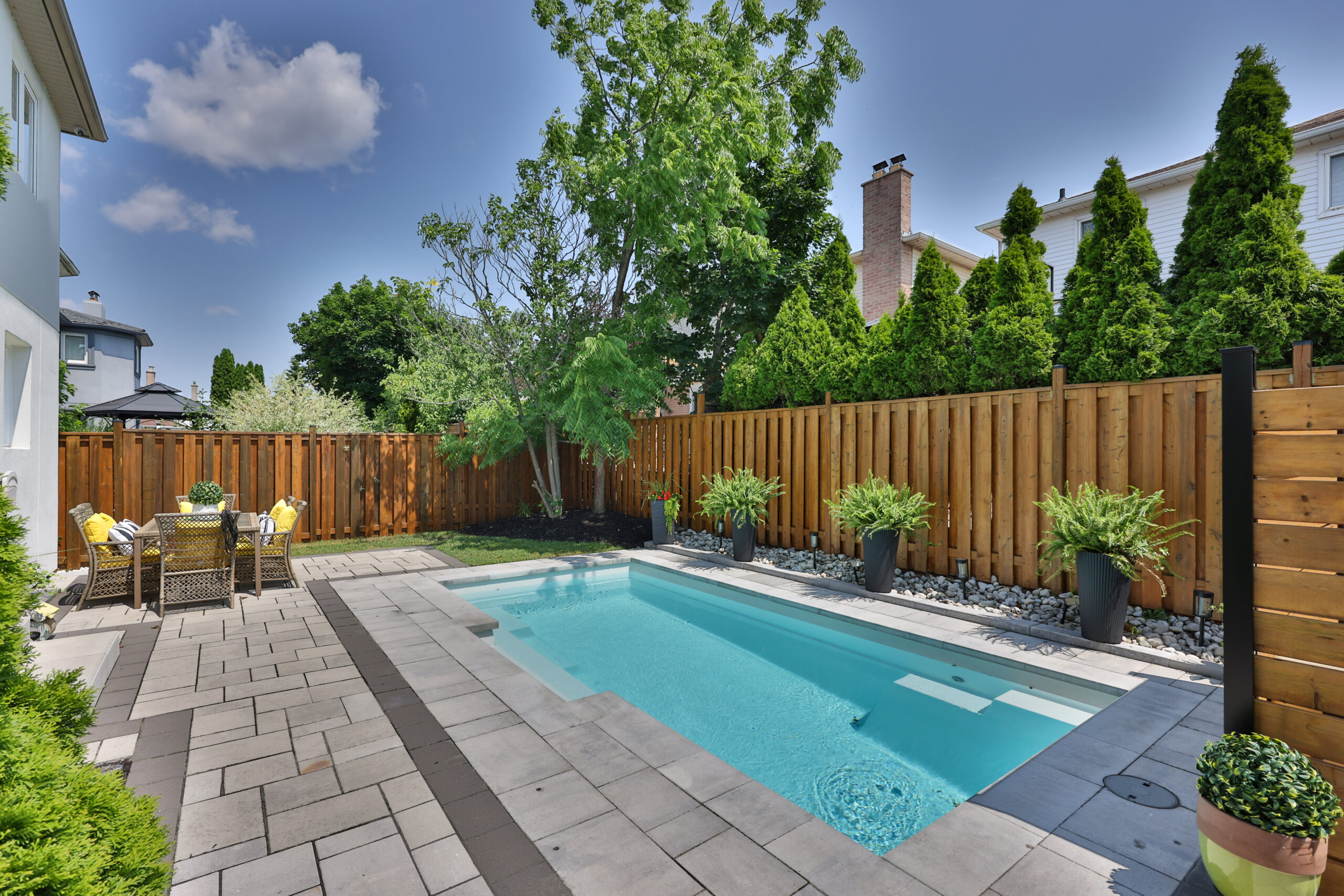Backyard pool area with a wooden fence and lush greenery