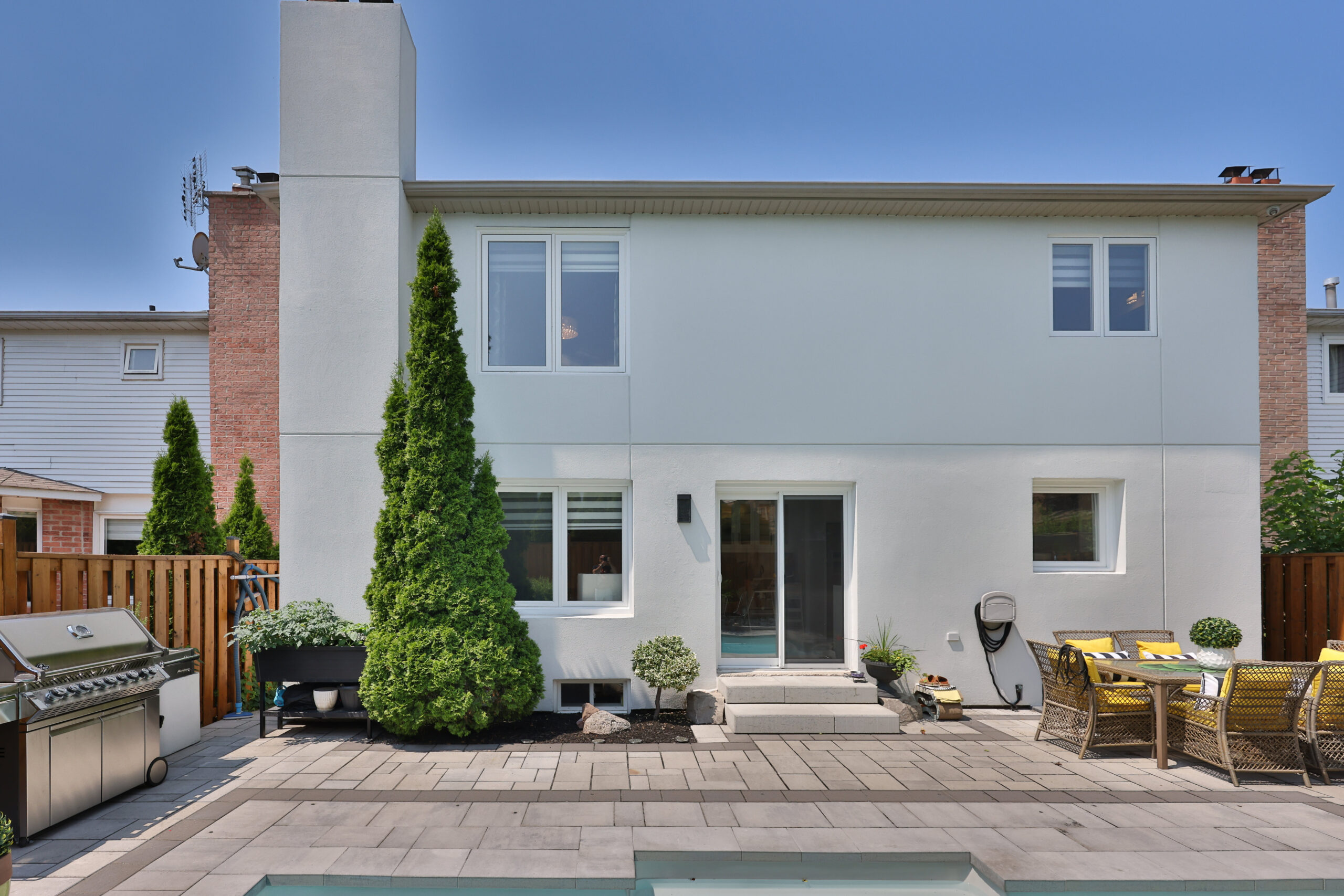 Modern two-story house with patio, grill, and seating area