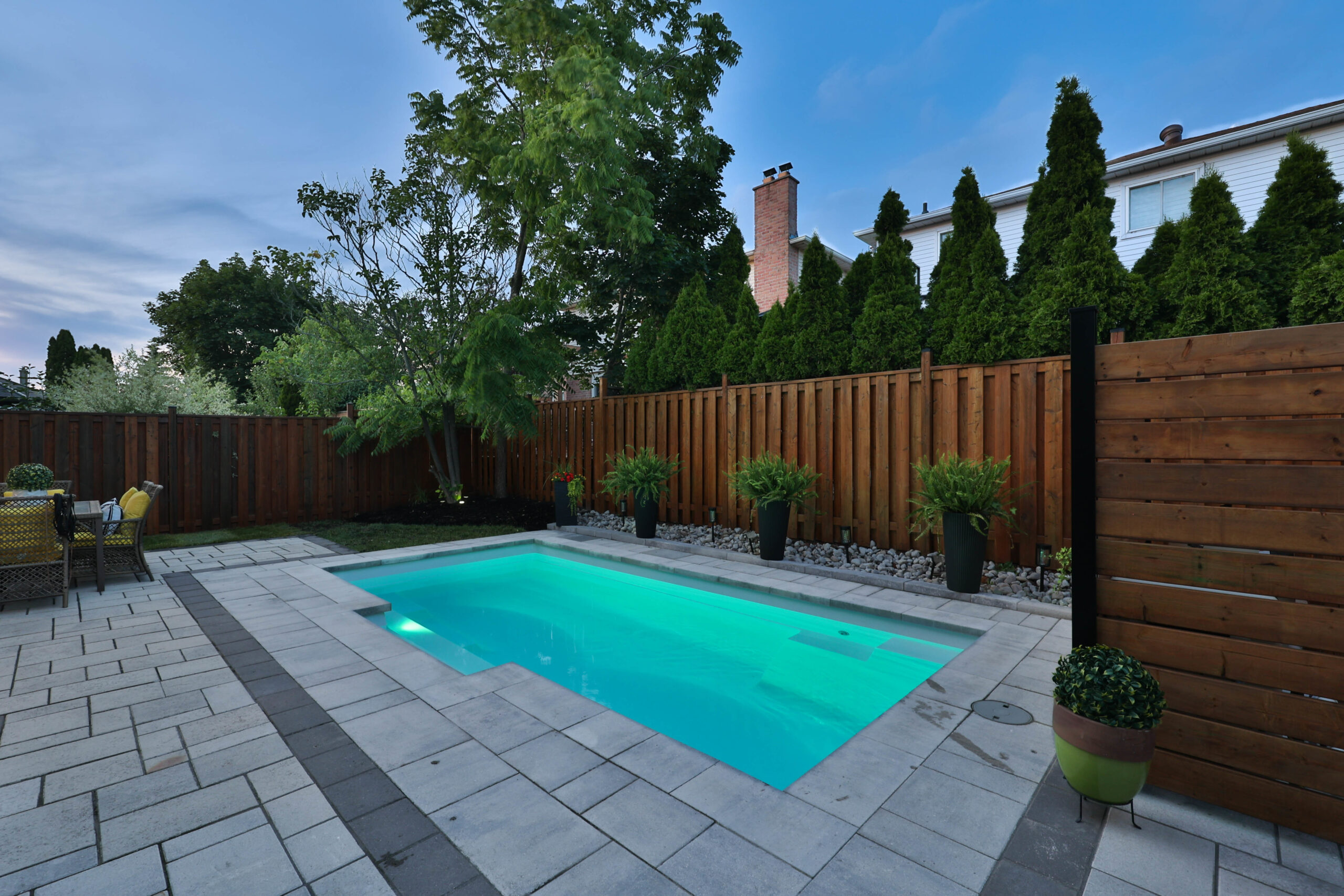 Backyard with a small pool surrounded by stone tiles and greenery