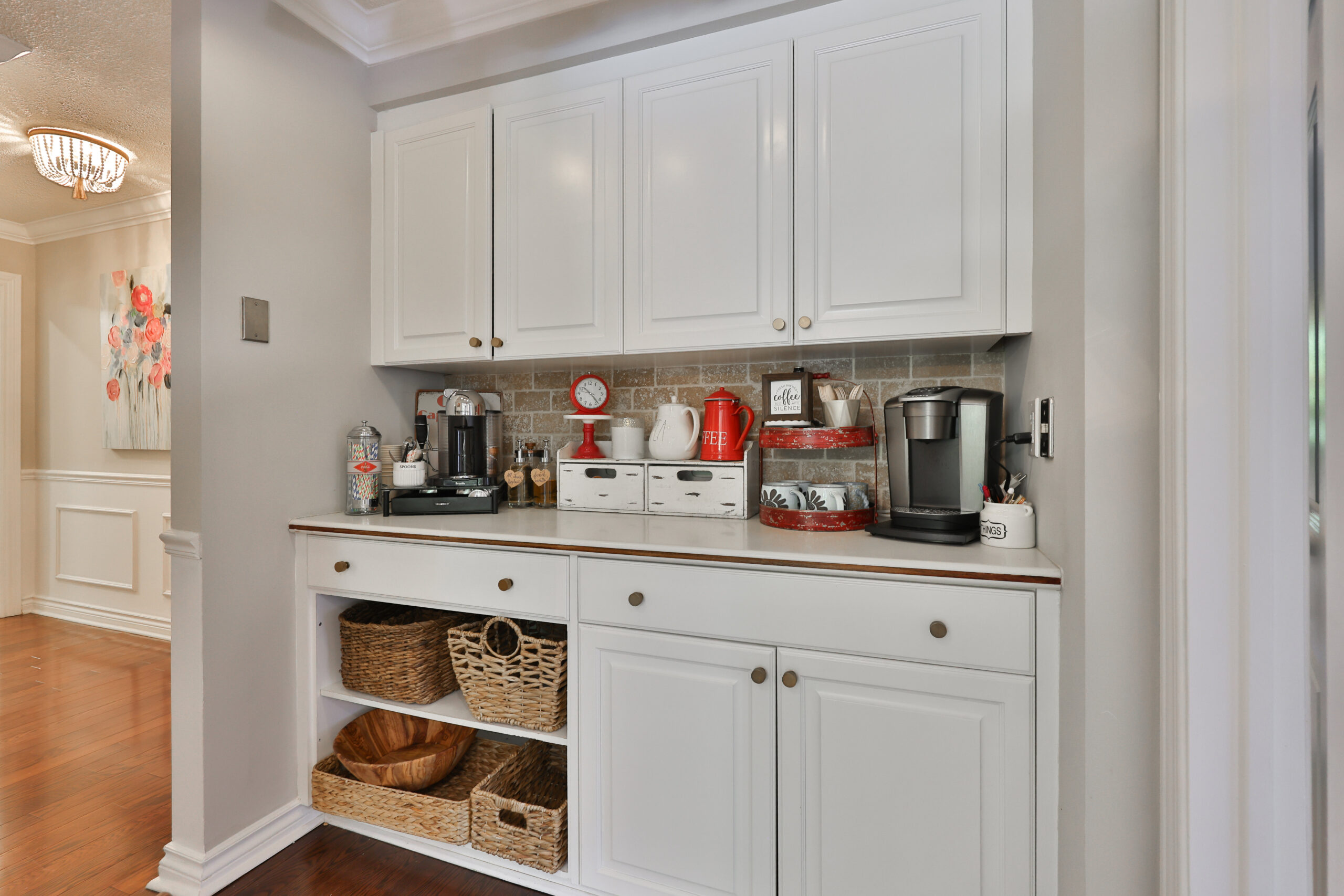 Modern kitchen nook with white cabinets, coffee machines, and woven baskets