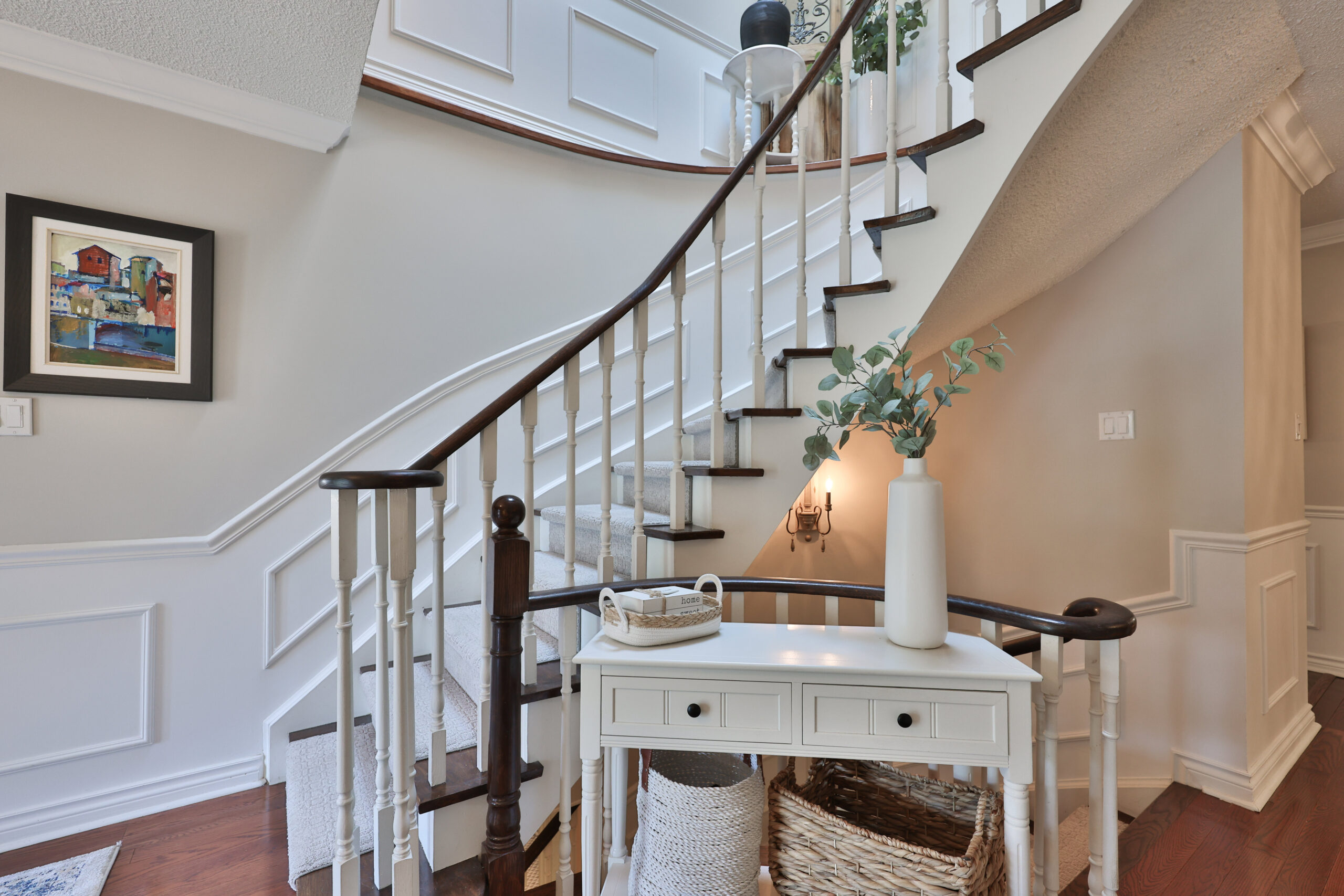 Elegant staircase with white railings and decorative table in foyer