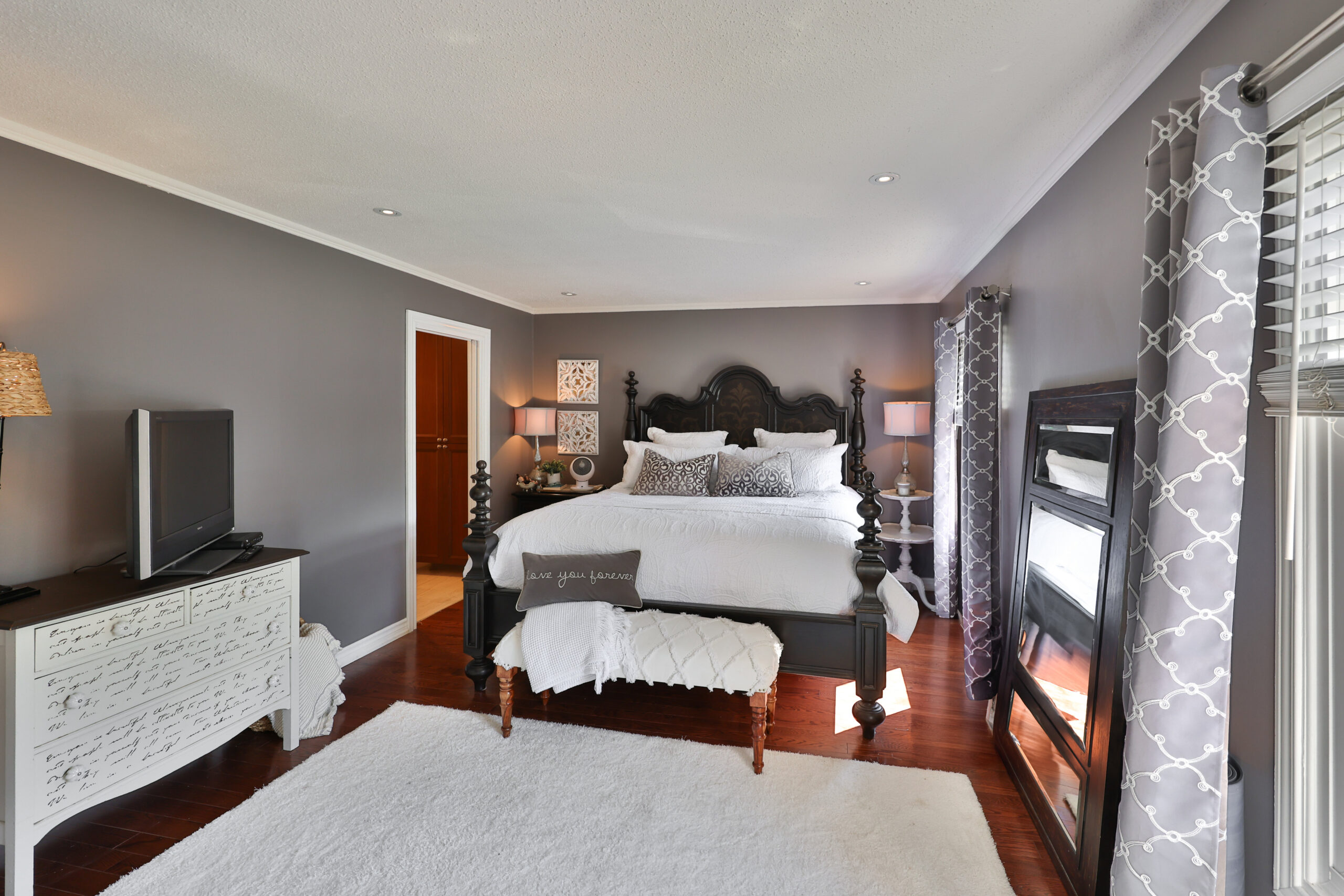 Spacious bedroom with dark furniture, gray walls, and a cozy atmosphere