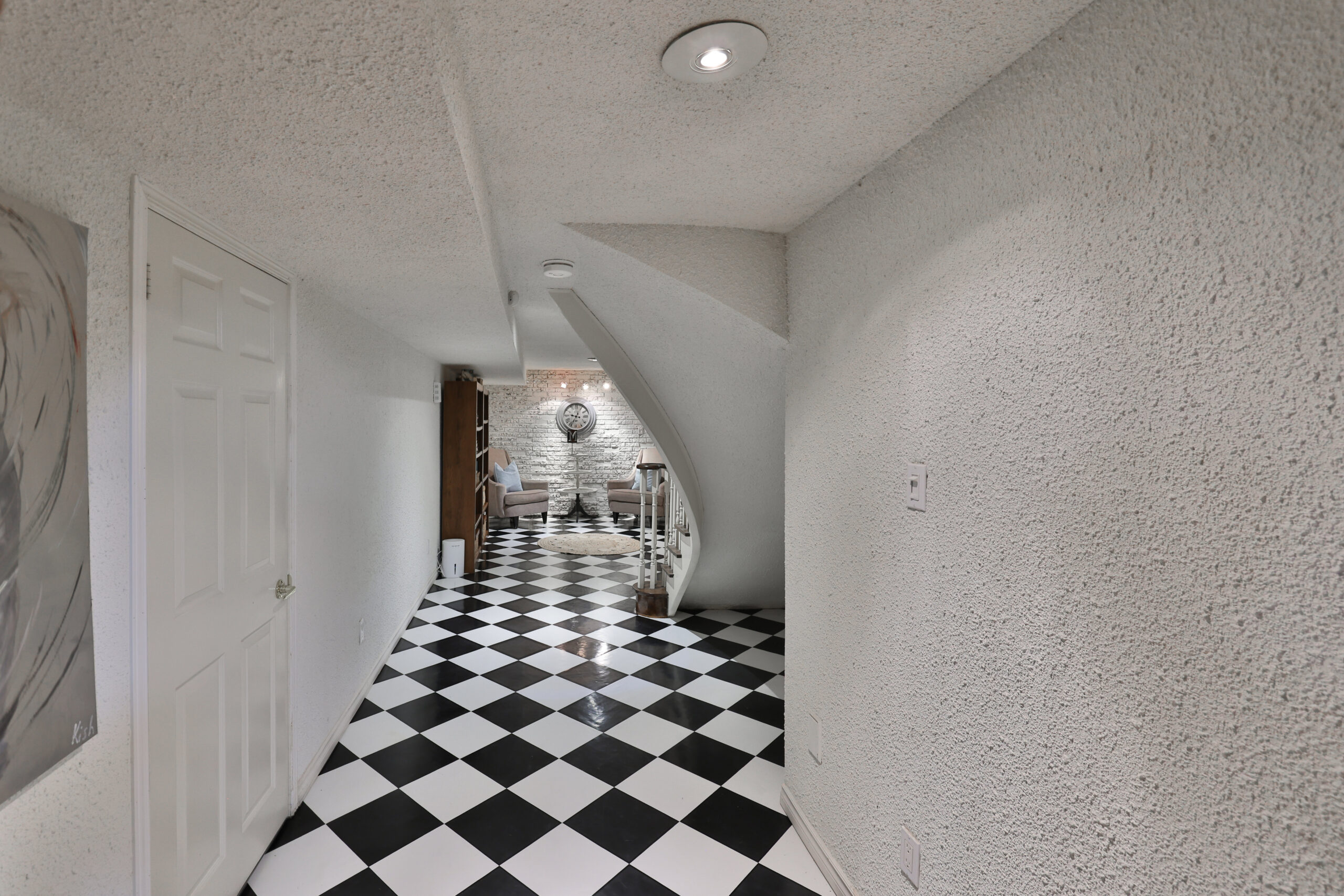 Black and white checkered flooring in a hallway with textured walls